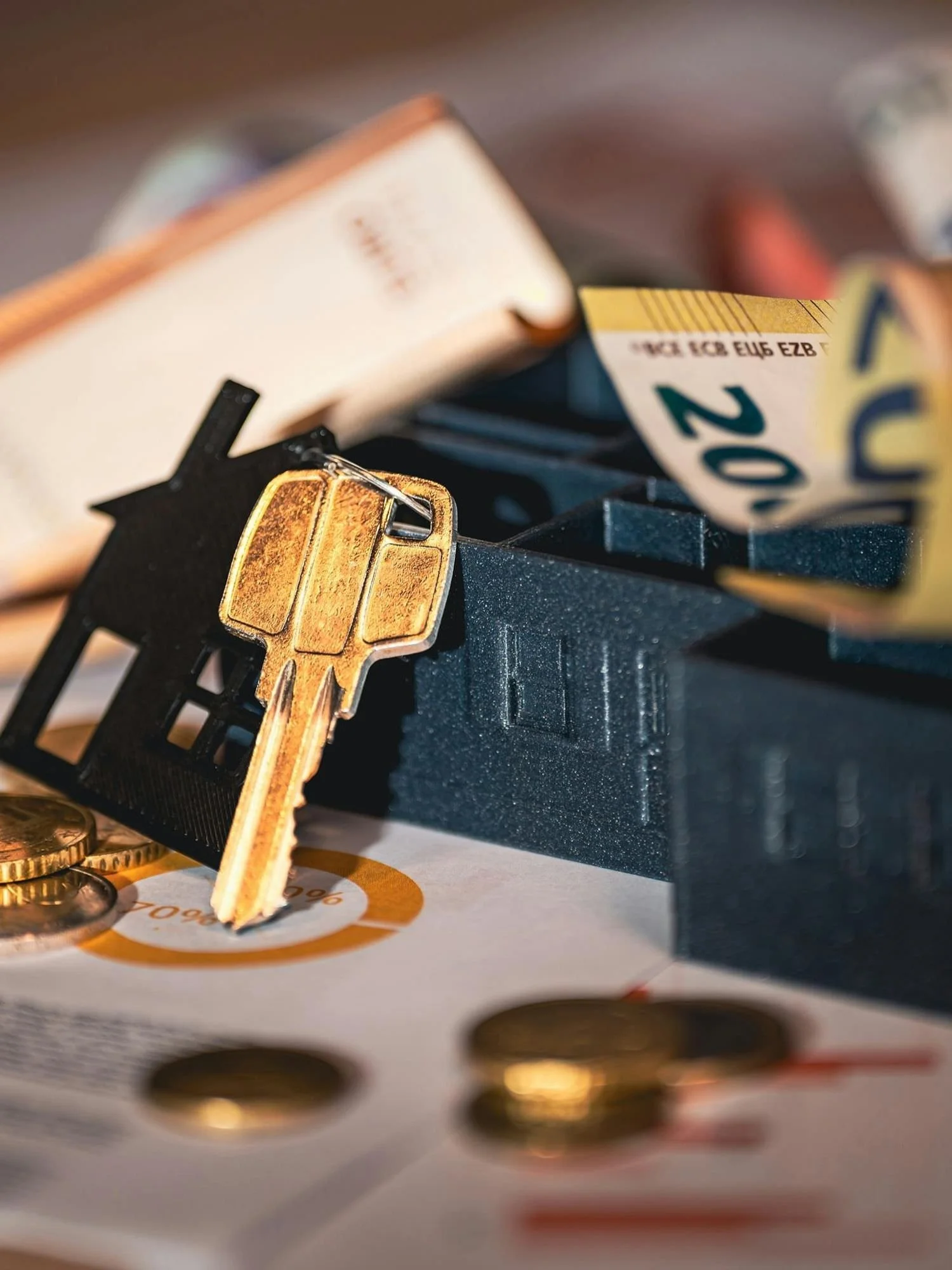 A gold key sitting against a cut out of a house