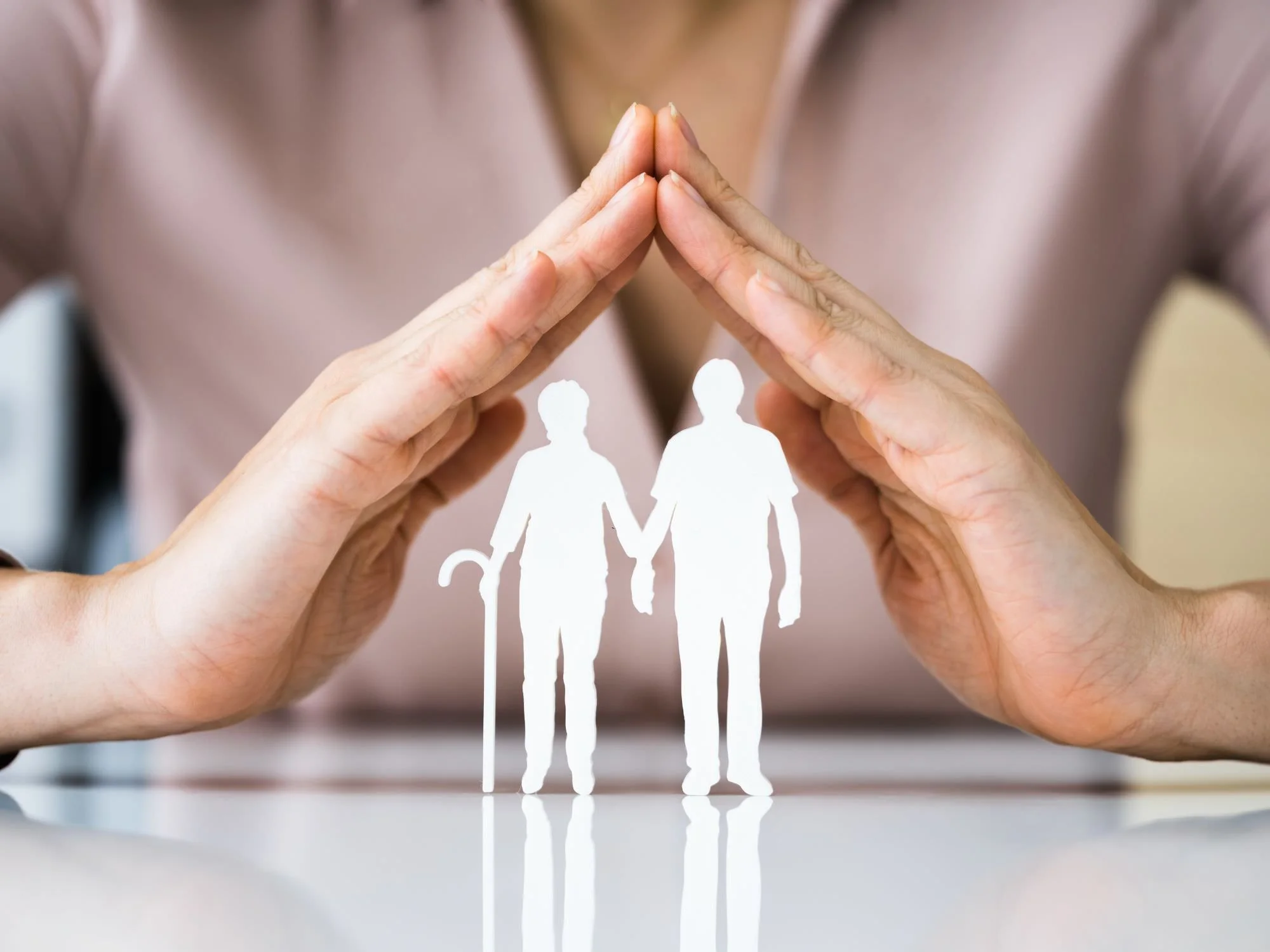 Woman with hands over a cut out of two old people.