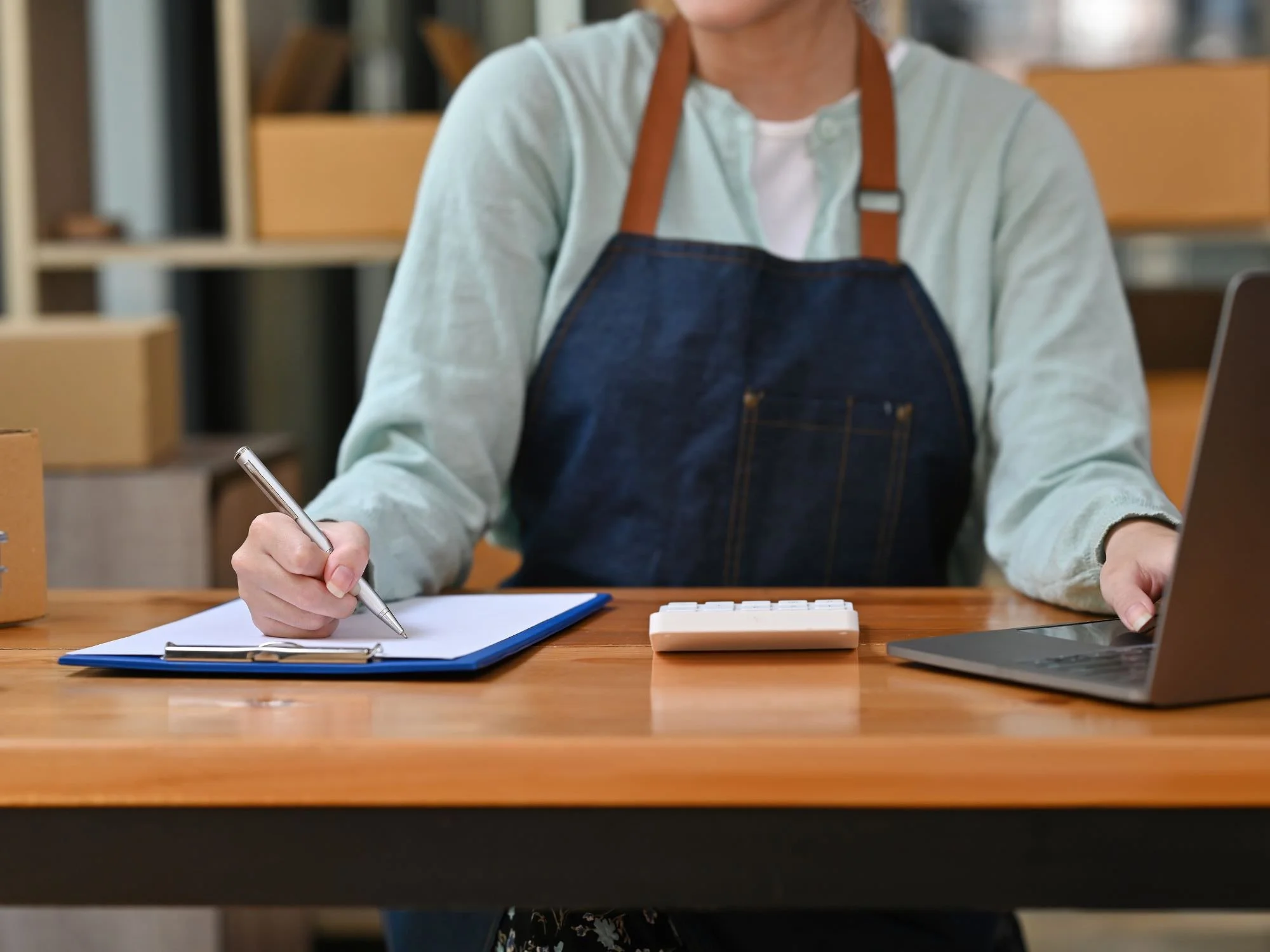 woman in apron writing something on clipboard - Financial Planning for Atlanta Business Owners