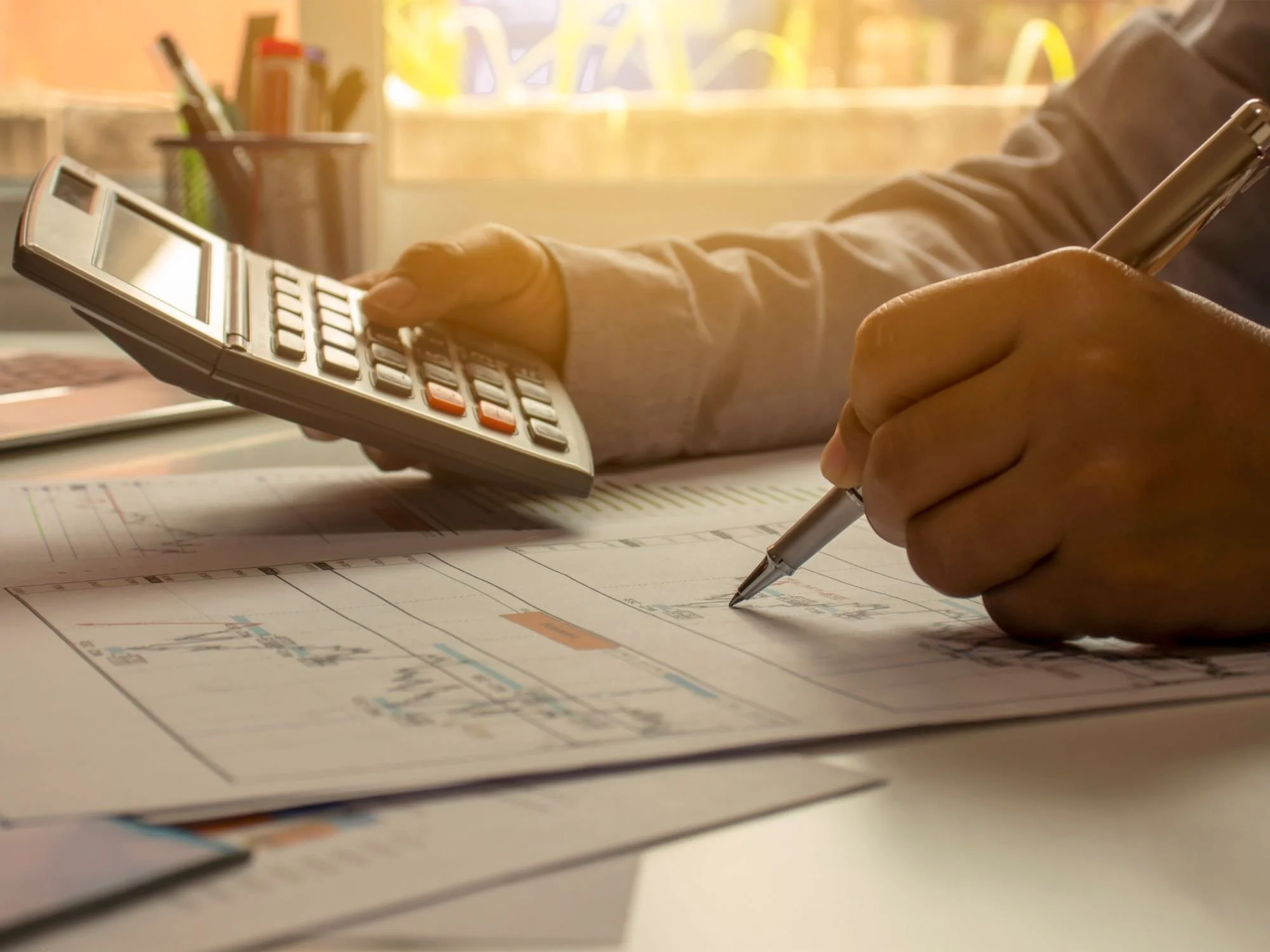 person looking at financials with pen in hand and calculator in the other - QRDO divorce