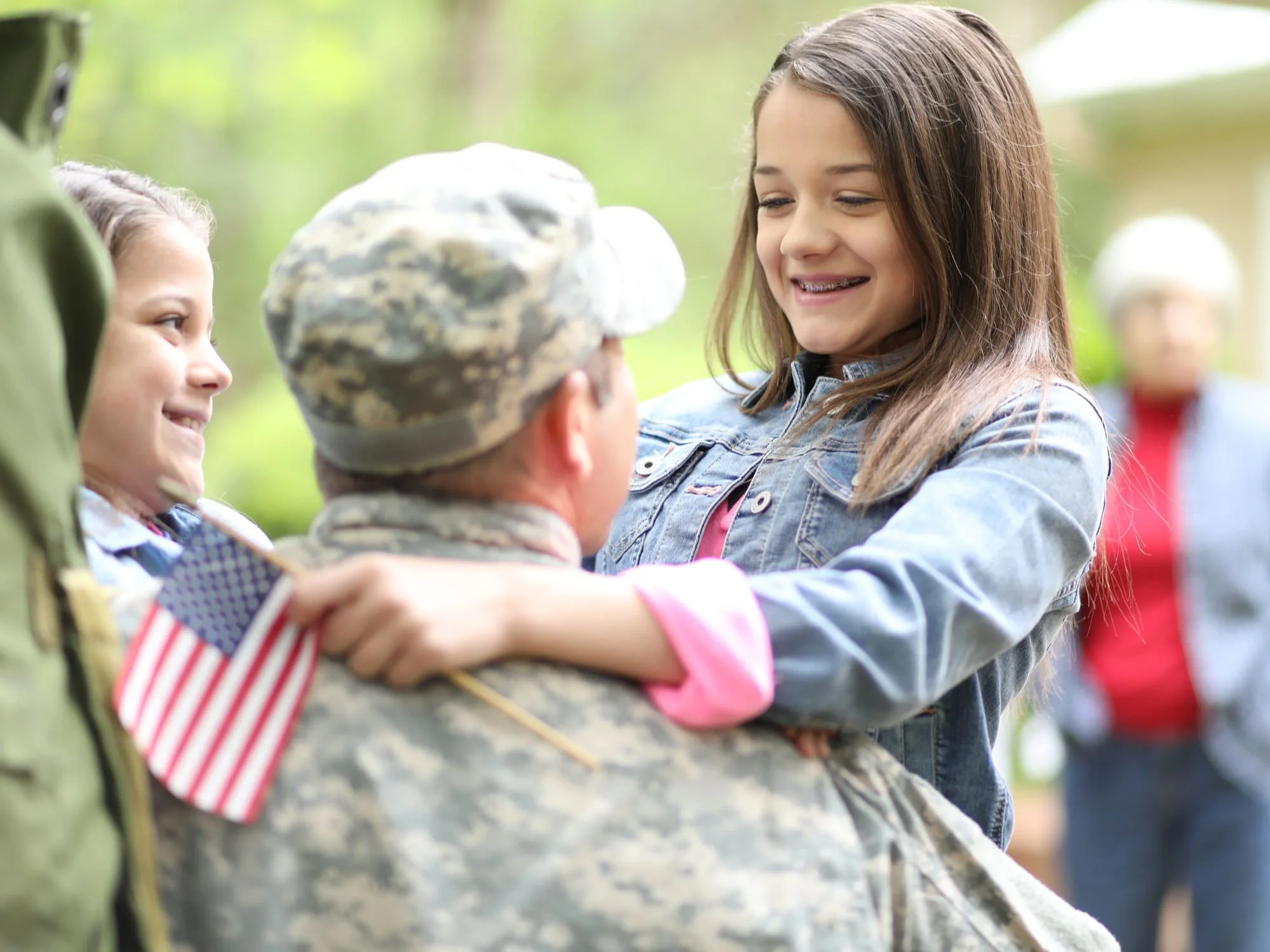 Man hugging his daughter who's holding an American flag.- Military Pension Divorce