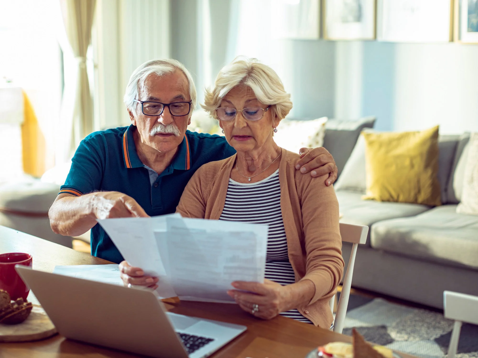 Older couple reviewing paperwork with a laptop
