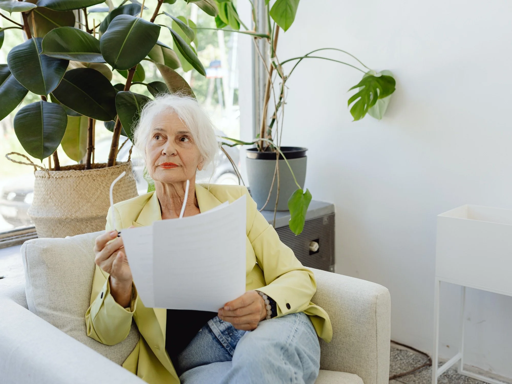 older woman in yellow sweater looking over documents