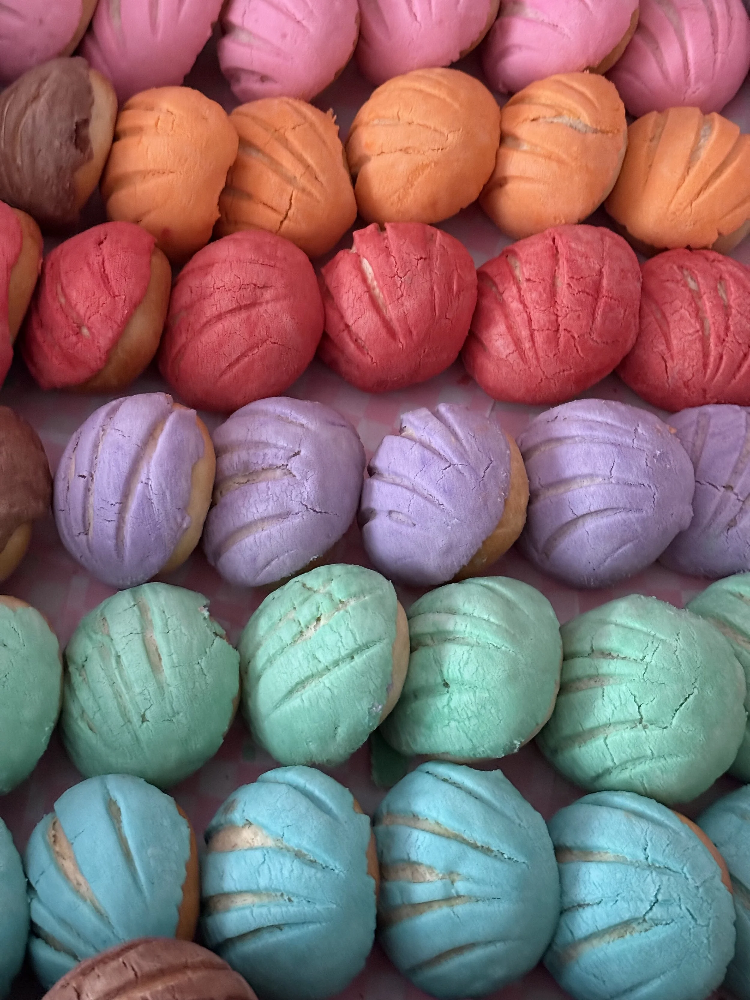 Colorful meringue cookies in pink, orange, purple, green, and blue, arranged in rows.