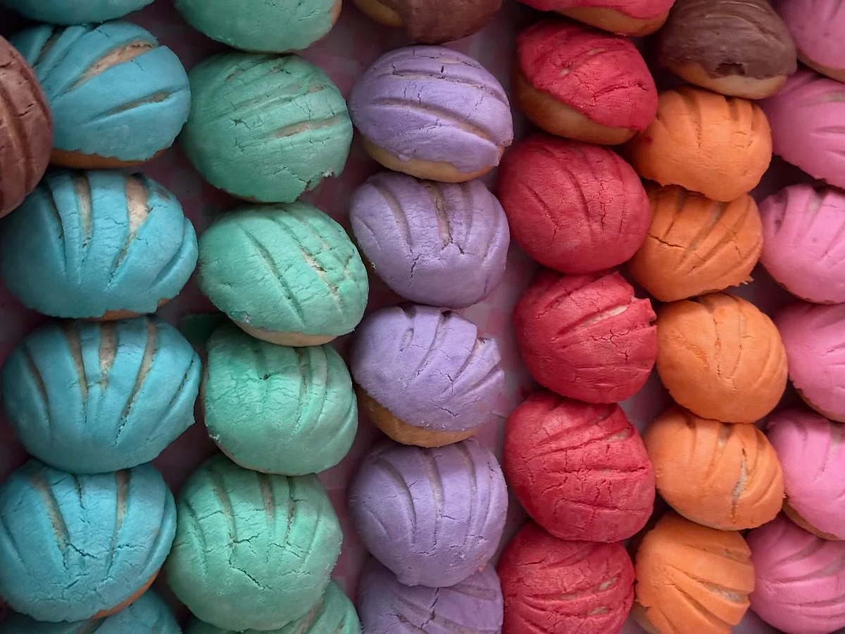 Colorful meringue cookies in shades of blue, green, purple, red, orange, and pink arranged in rows.