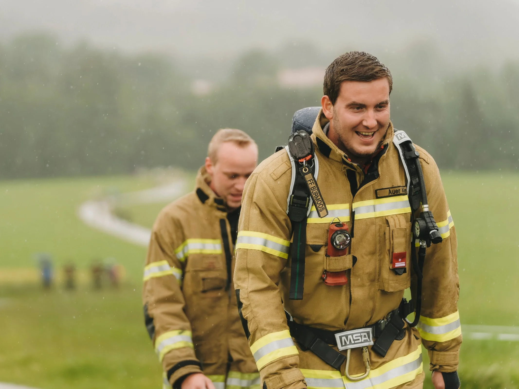 Zwei Feuerwehrmänner in Uniform auf der Strecke beim Charitylauf lauf:feuer 2024 in Elixhausen