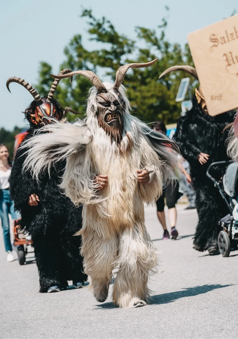 Krampusse laufen gemeinsam mit Teilnehmerinnen und Teilnehmern auf der Strecke beim Charitylauf lauf:feuer 2023 in Elixhausen
