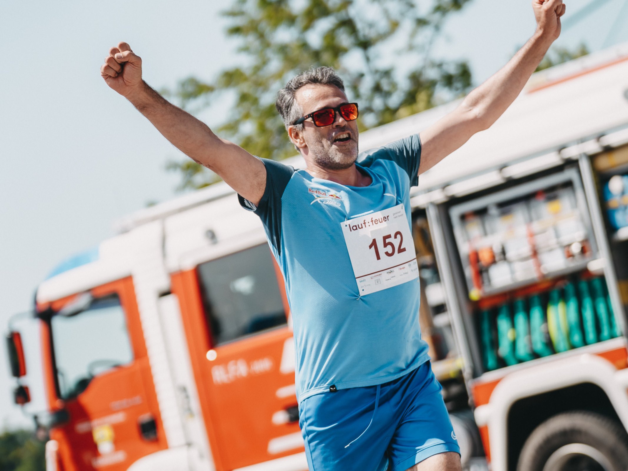 Dr. Daniel Weghuber läuft mit erhobenen Händen ins Ziel beim Charitylauf lauf:feuer 2023 in Elixhausen