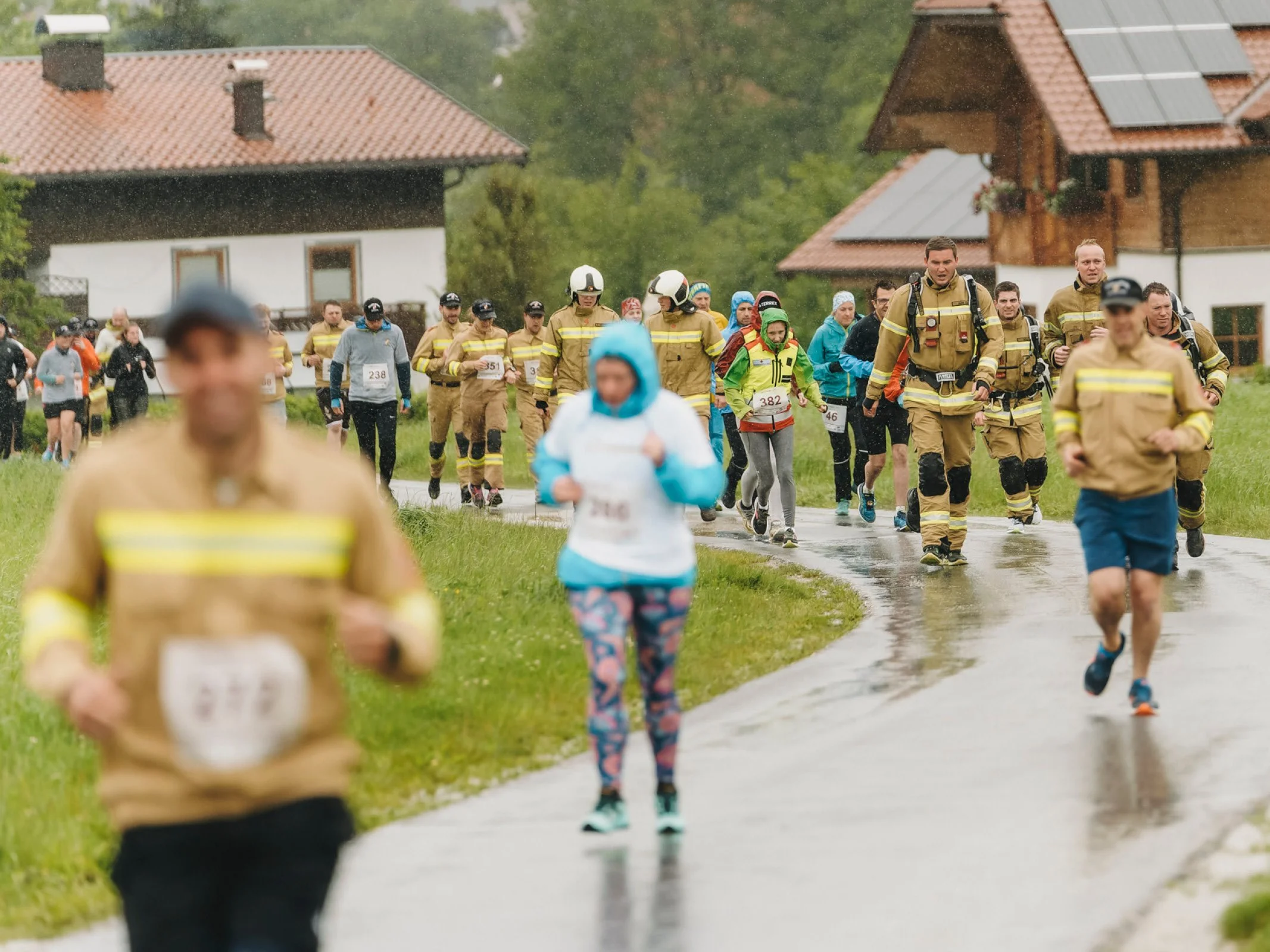 Viele Teilnehmerinnen und Teilnehmer, darunter Feuerwehr in Uniform, auf der Laufstrecke beim Charitylauf lauf:feuer 2024 in Elixhausen