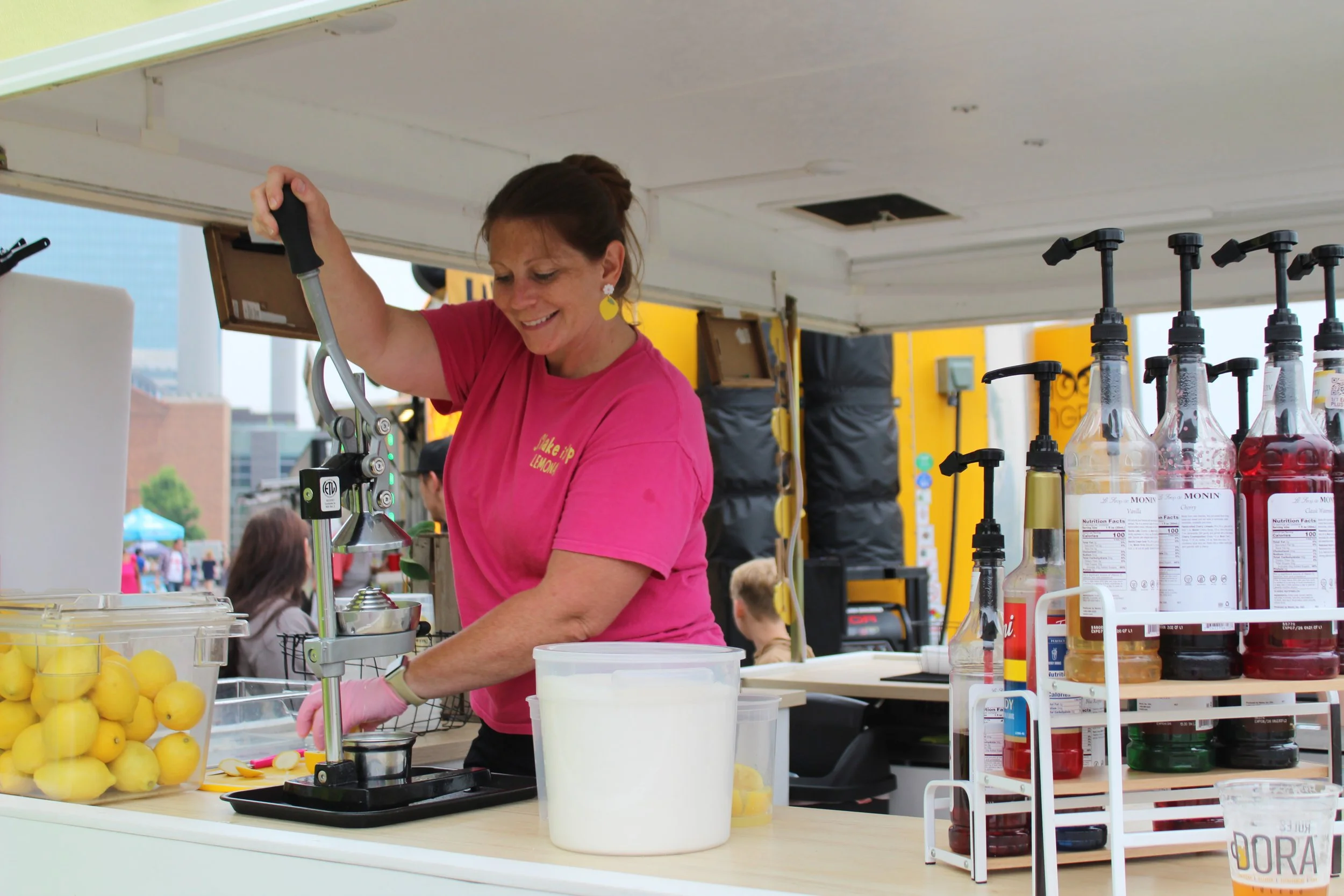 Shake It Up Lemonade team member squeezing fresh lemons at Strawberry Fest in Coldwater Michigan