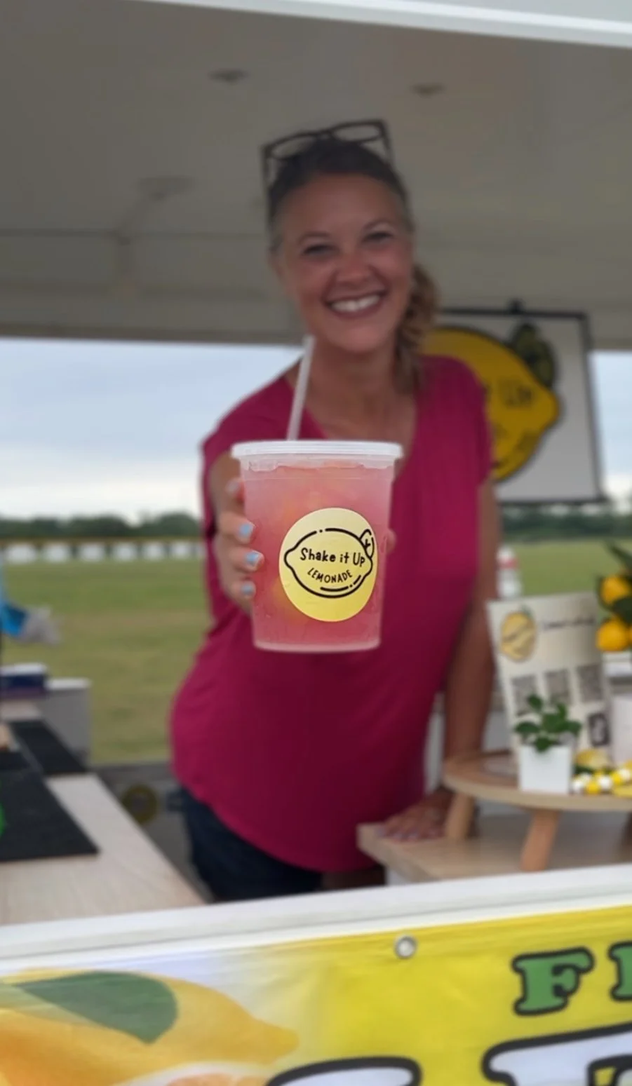 Shake It Up Lemonade crew member holding a drink at outdoor event