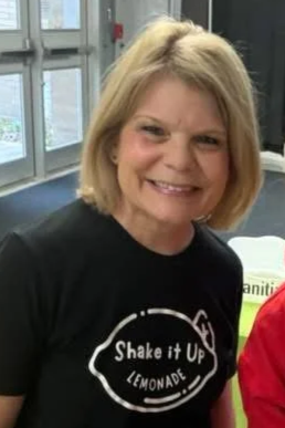 Shake It Up Lemonade team member Debbie smiling indoors at Wrestling Tournament