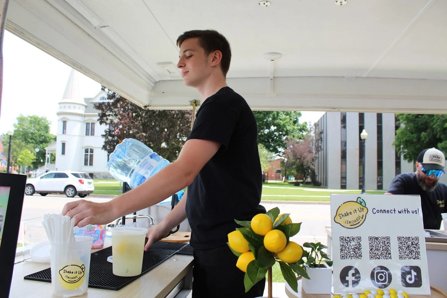 Shake It Up Lemonade team member serving lemonade from trailer at Toledo Westgate Farmers Market, Toledo, Ohio