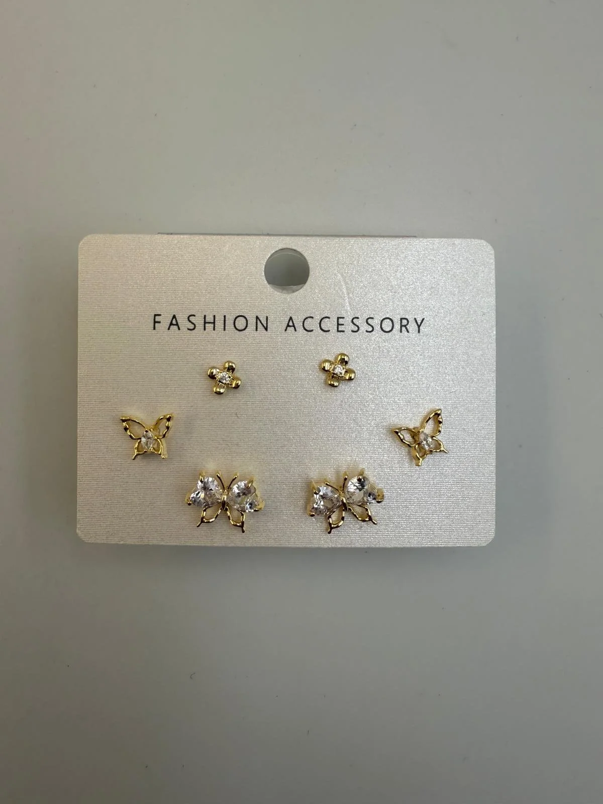 Set of three pairs of butterfly and floral earrings on a white card labeled 'Fashion Accessory'