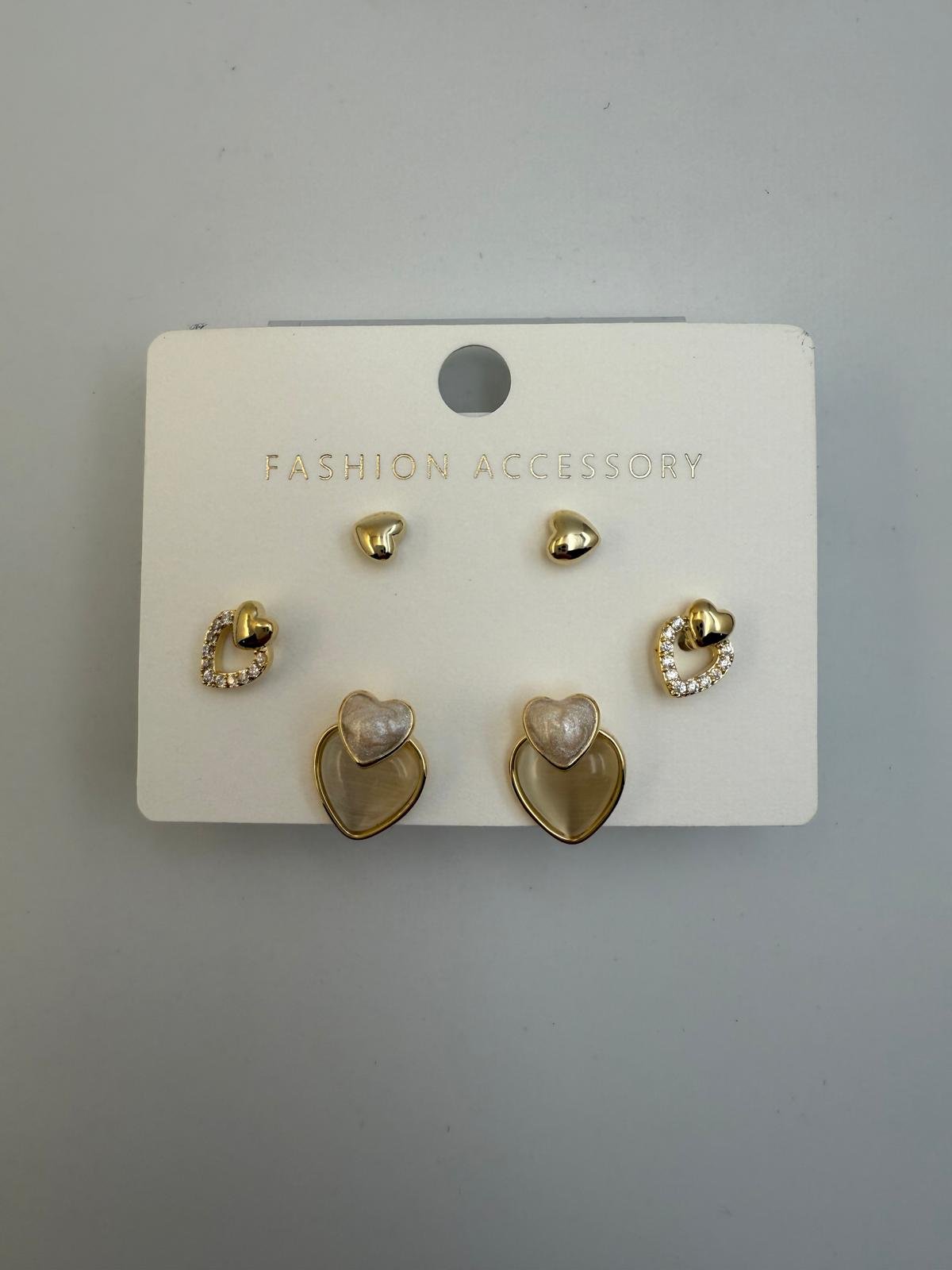 Set of four pairs of earrings on a white display card labeled 'Fashion Accessory' with four different styles, including heart shapes and rhinestone embellishments.