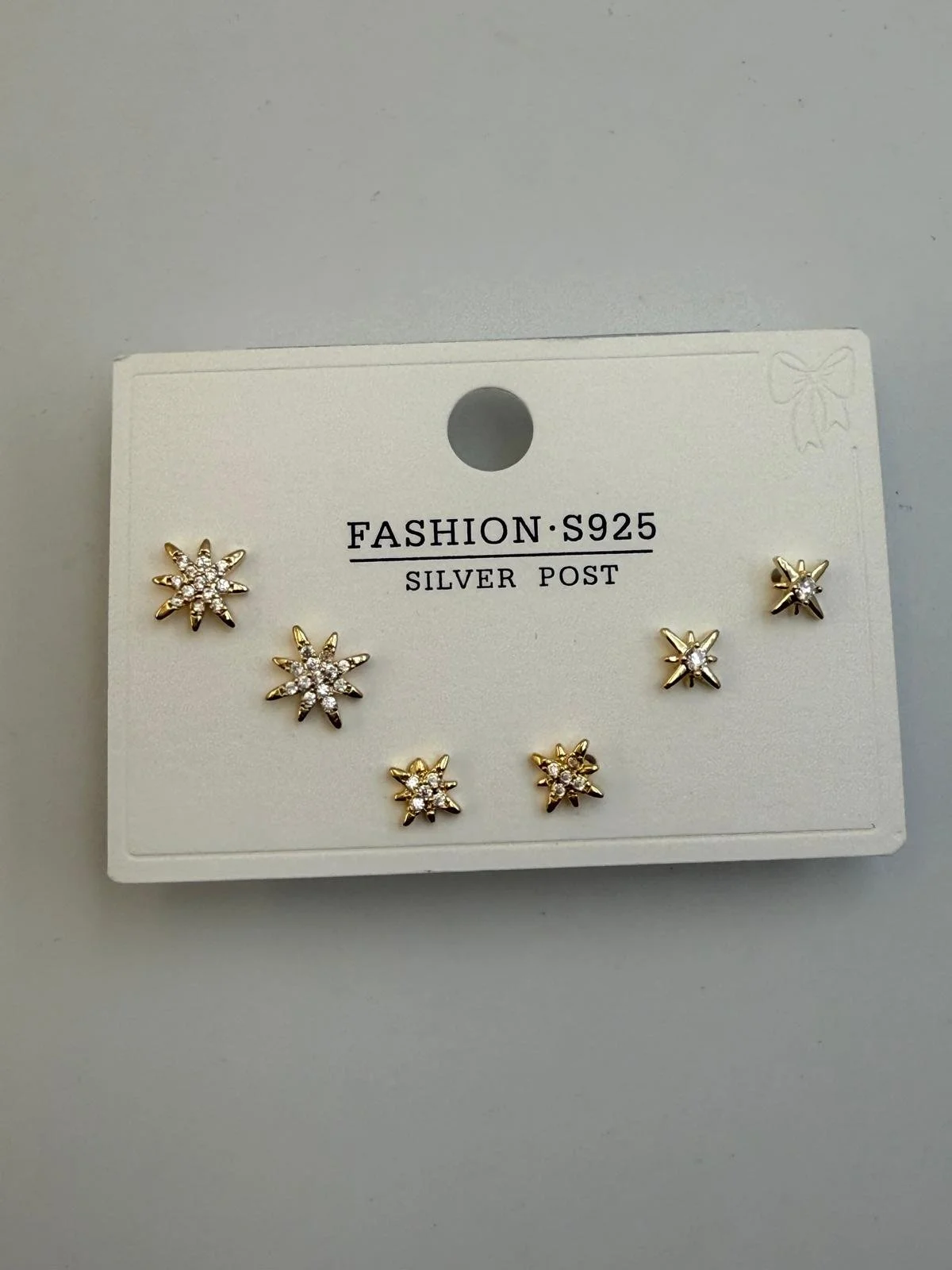 Set of six star-shaped earrings with small crystals, gold and silver in color, on a white display card marked 'FASHION S925 SILVER POST'.
