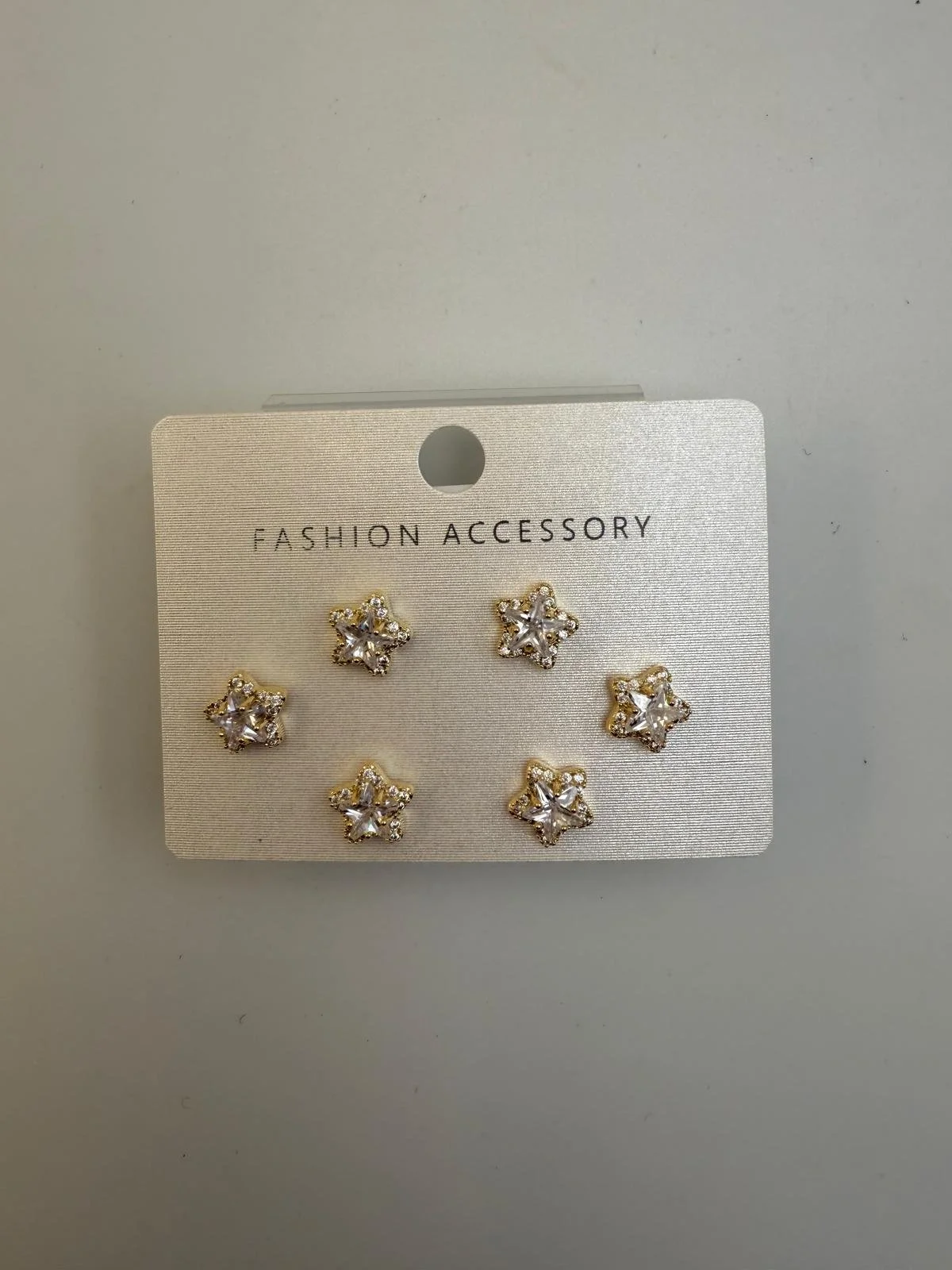 Six star-shaped earrings with clear stones on a white card labeled "Fashion Accessory."