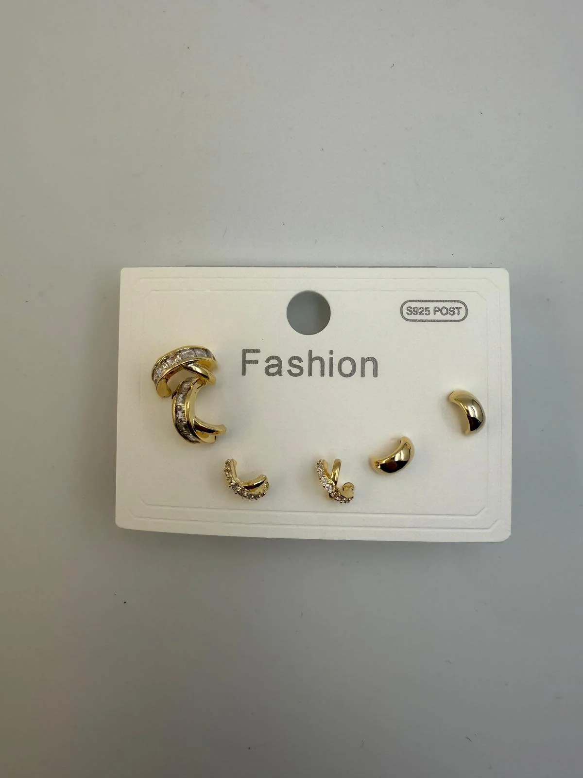 A set of gold and silver earrings with rhinestones on a white card labeled 'Fashion'