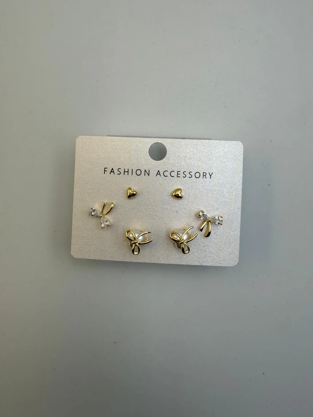 Set of three pairs of gold and silver earrings on a white display card labeled 'Fashion Accessory'.