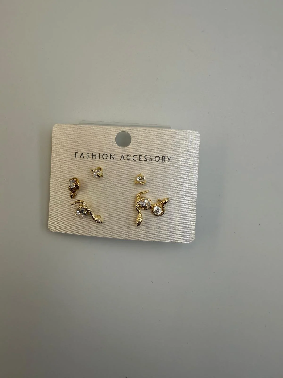 Set of gold earrings with clear gemstones displayed on a white card labeled 'Fashion Accessory'.