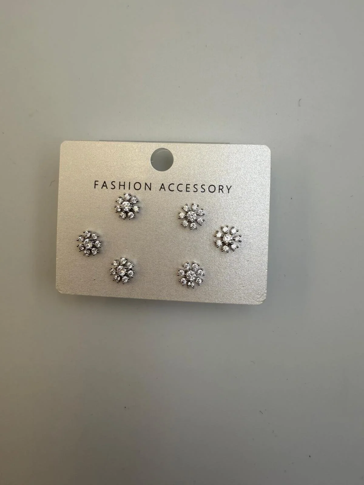 Set of six pairs of silver floral-shaped stud earrings with clear rhinestones, attached to a white card labeled "Fashion Accessory."