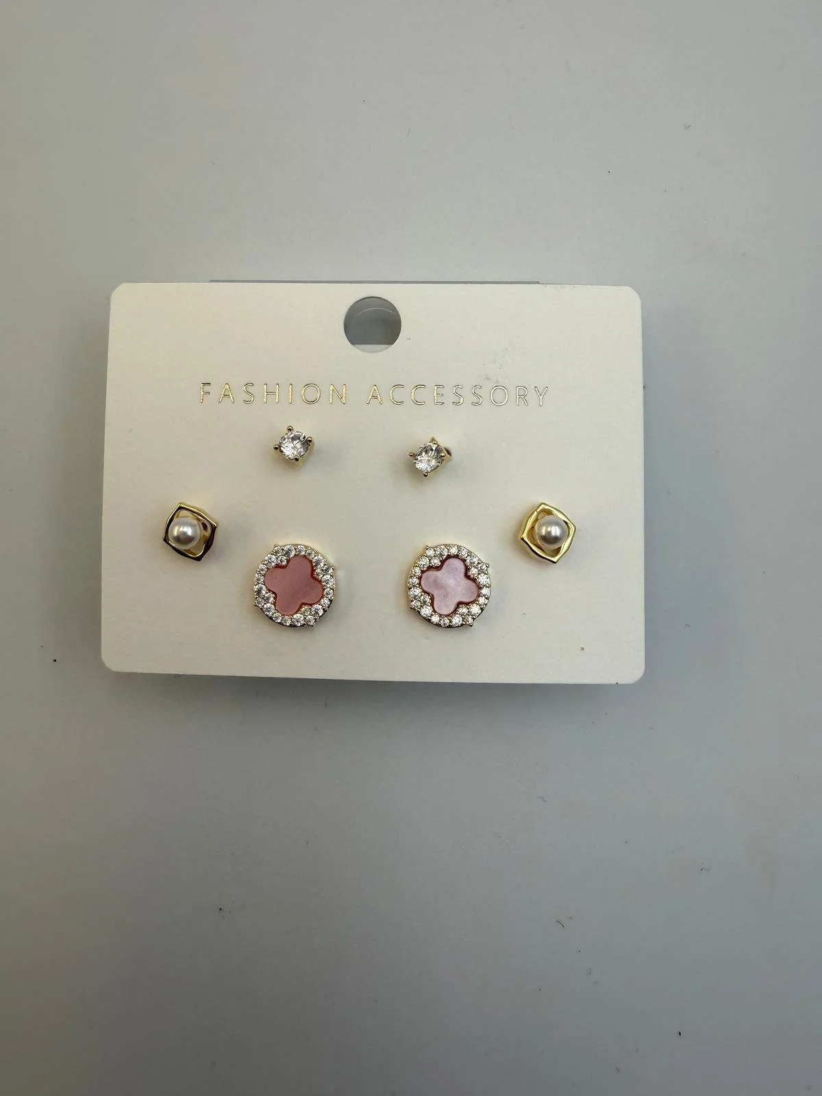 Set of five fashion earrings attached to a white card labeled 'Fashion Accessory'. The earrings include small stud earrings with clear stones, pearl earrings with gold frames, and pink and clear flower-shaped earrings with rhinestones.