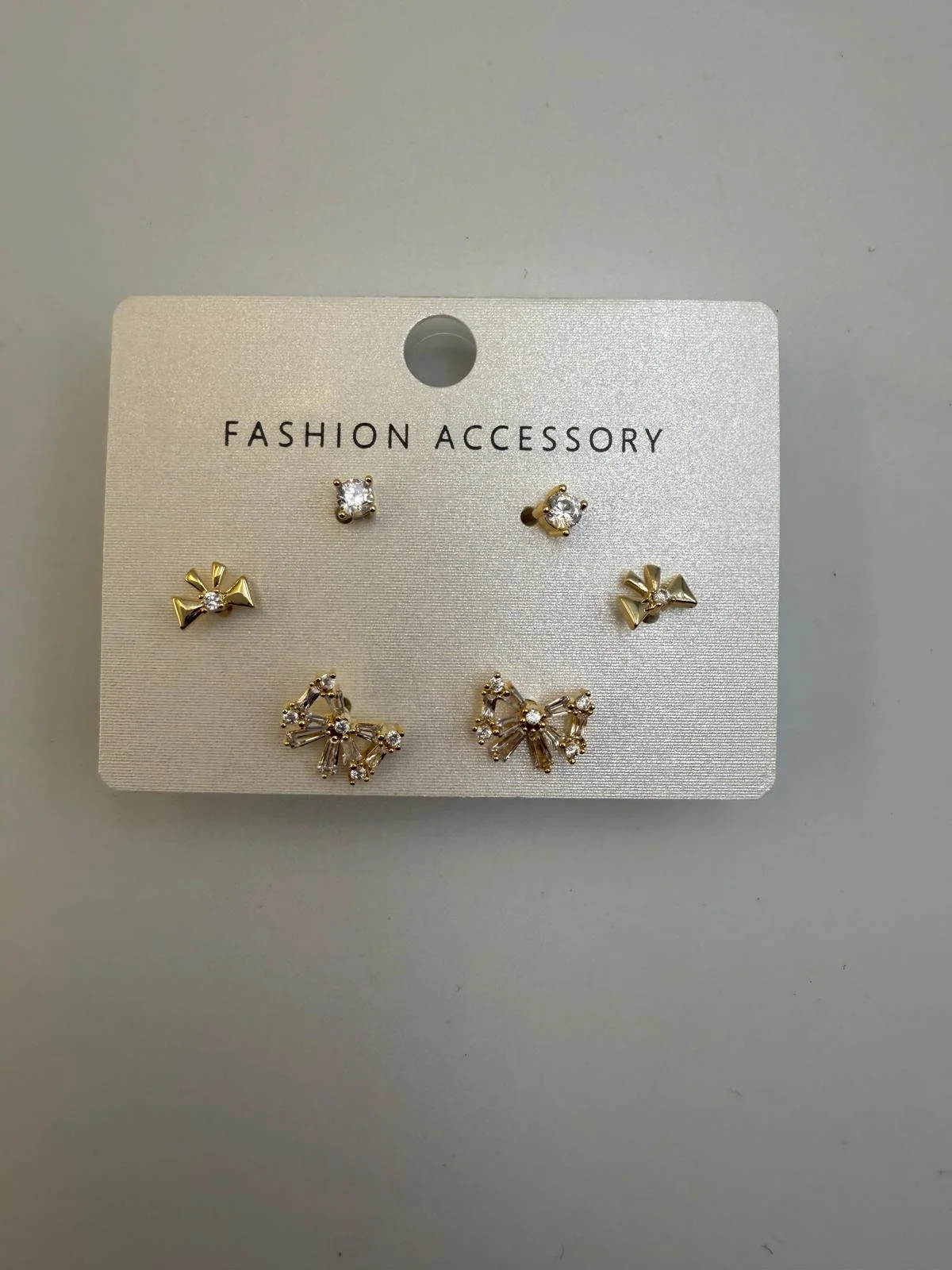 Set of five gold earrings with rhinestones, arranged on a white card labeled 'Fashion Accessory'.