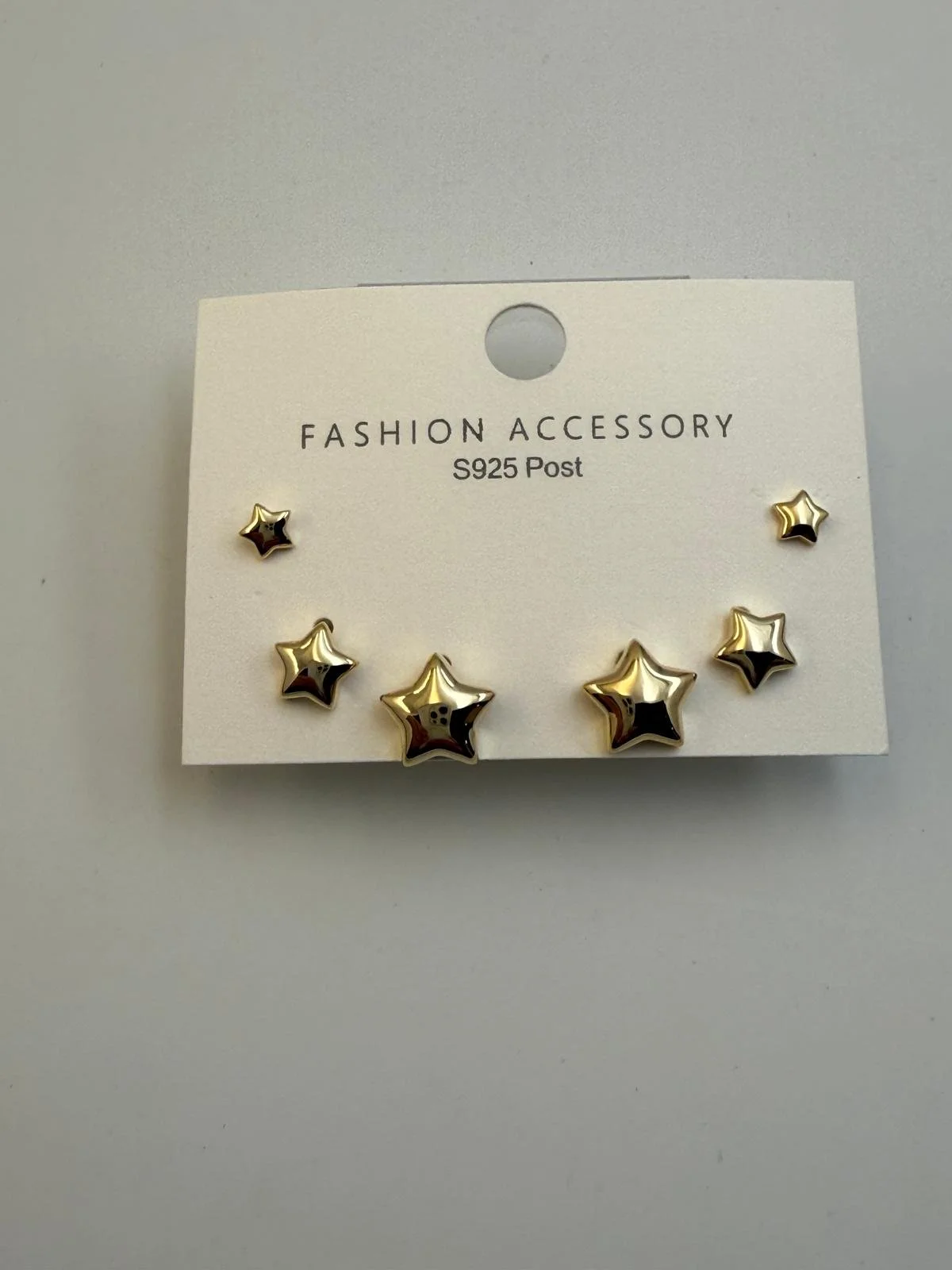 Set of gold star-shaped earrings on a white display card labeled 'FASHION ACCESSORY S925 Post'.