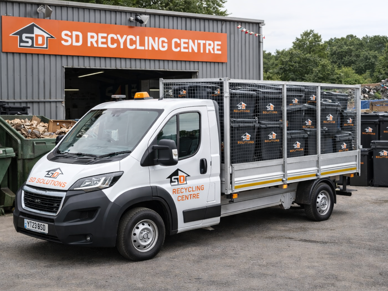 Recycling truck parked outside SD Recycling Centre with bins and waste materials.
