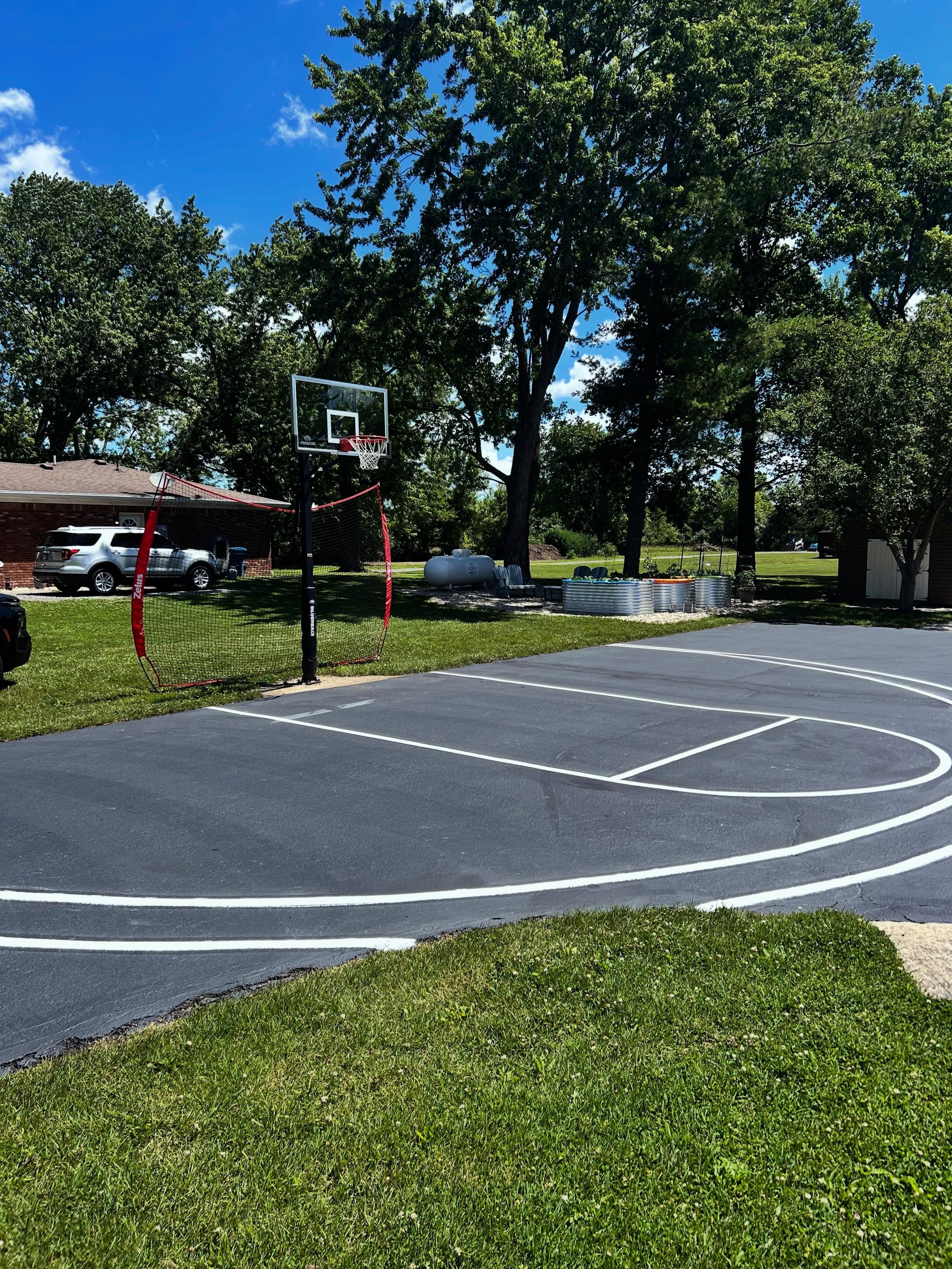 A driveway in Danville, Indiana with a basketball court striped by Blacktop Boss on top of fresh sealcoat.  