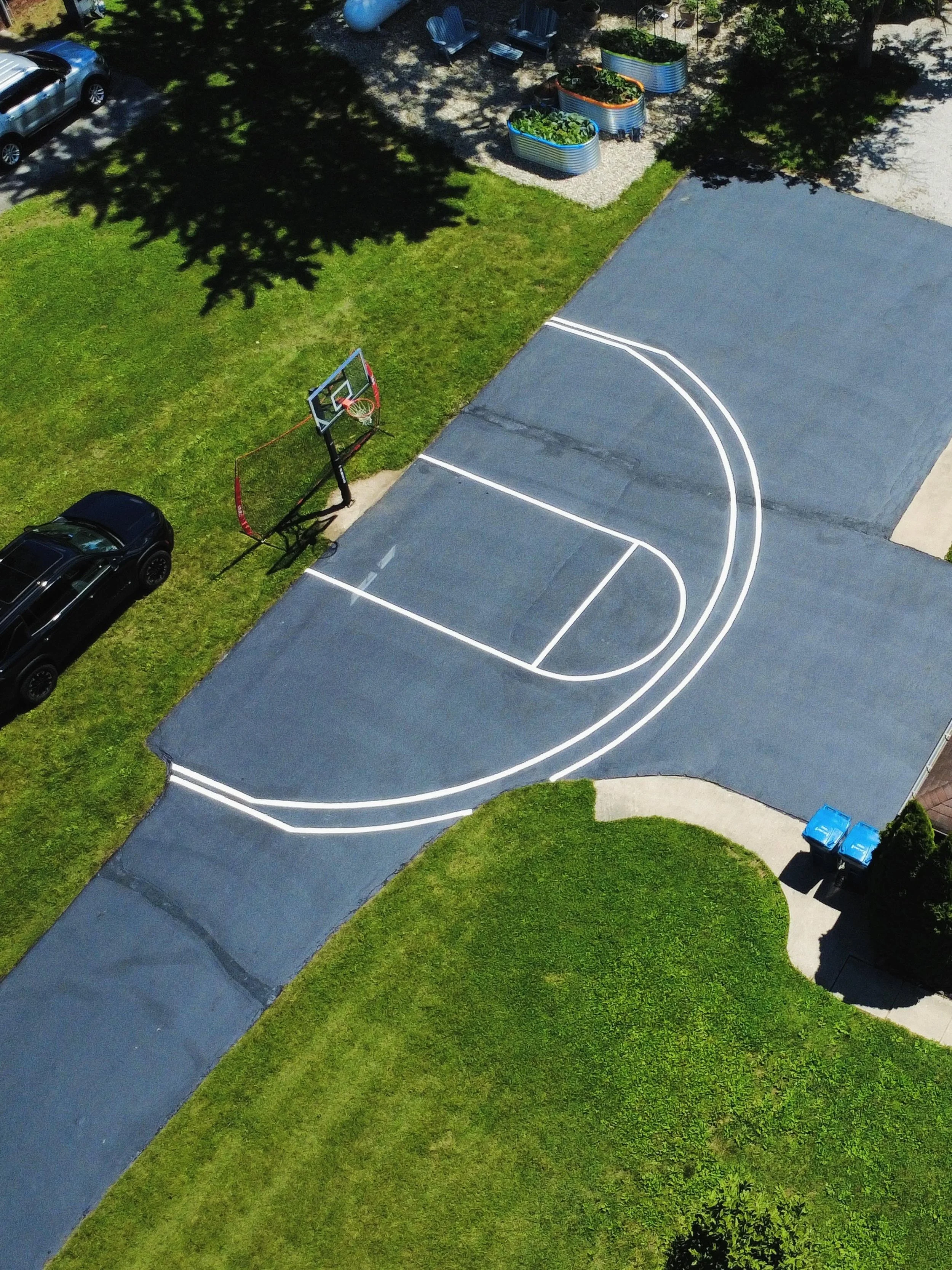 A driveway in Danville, Indiana with a basketball court striped by Blacktop Boss on top of a fresh sealcoat.  