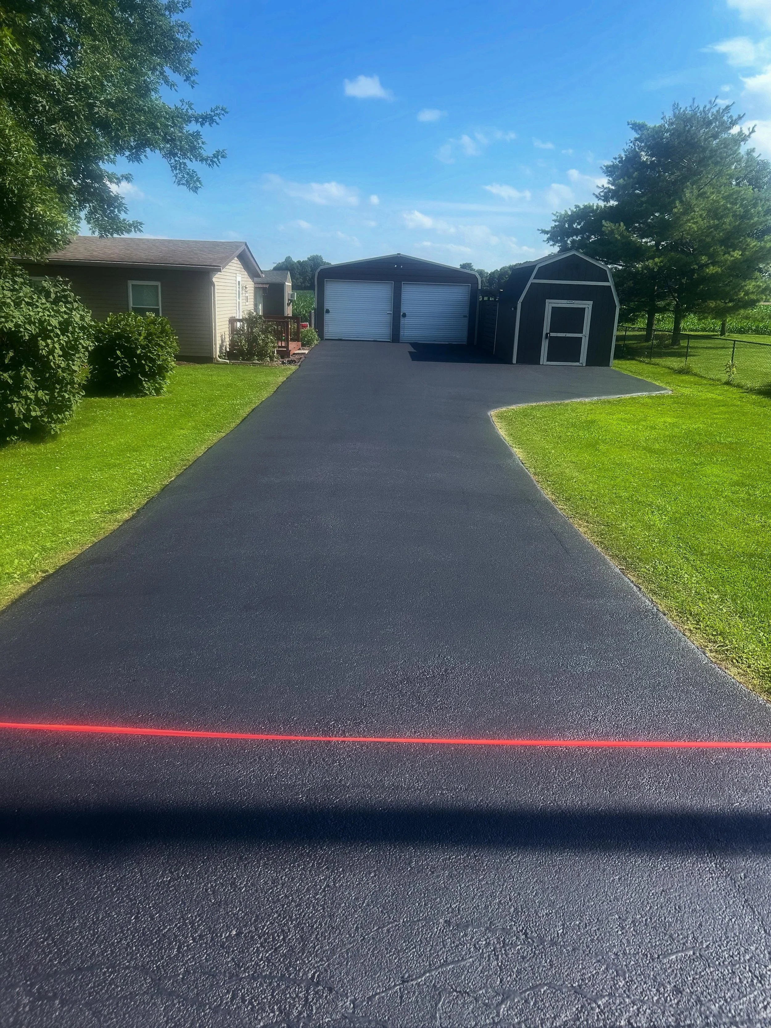 A driveway in Trafalgar, Indiana with a fresh sealcoat completed by Blacktop Boss. 