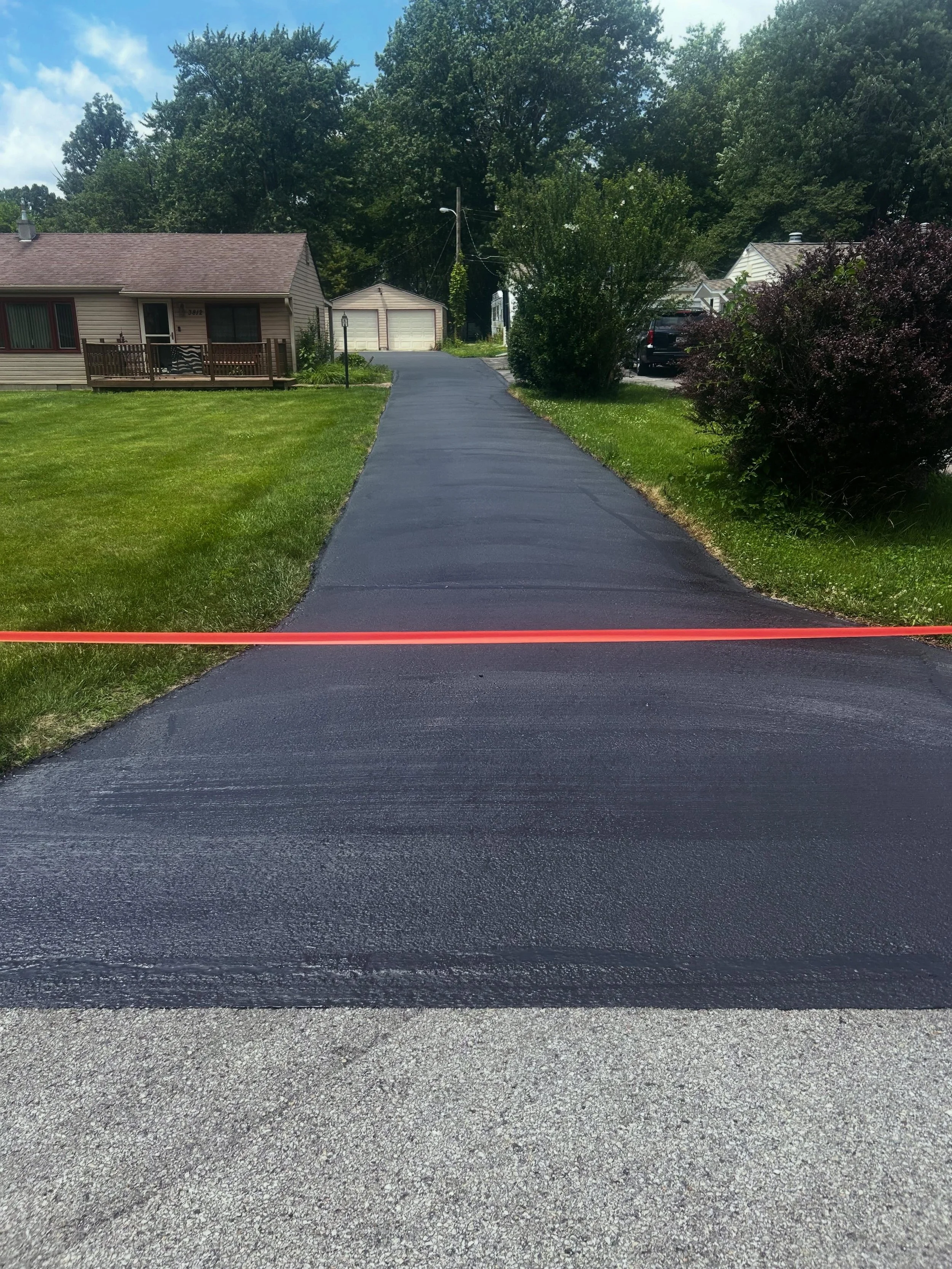 A residential driveway in Indianapolis, Indiana with a fresh sealcoat completed by Blacktop Boss. 