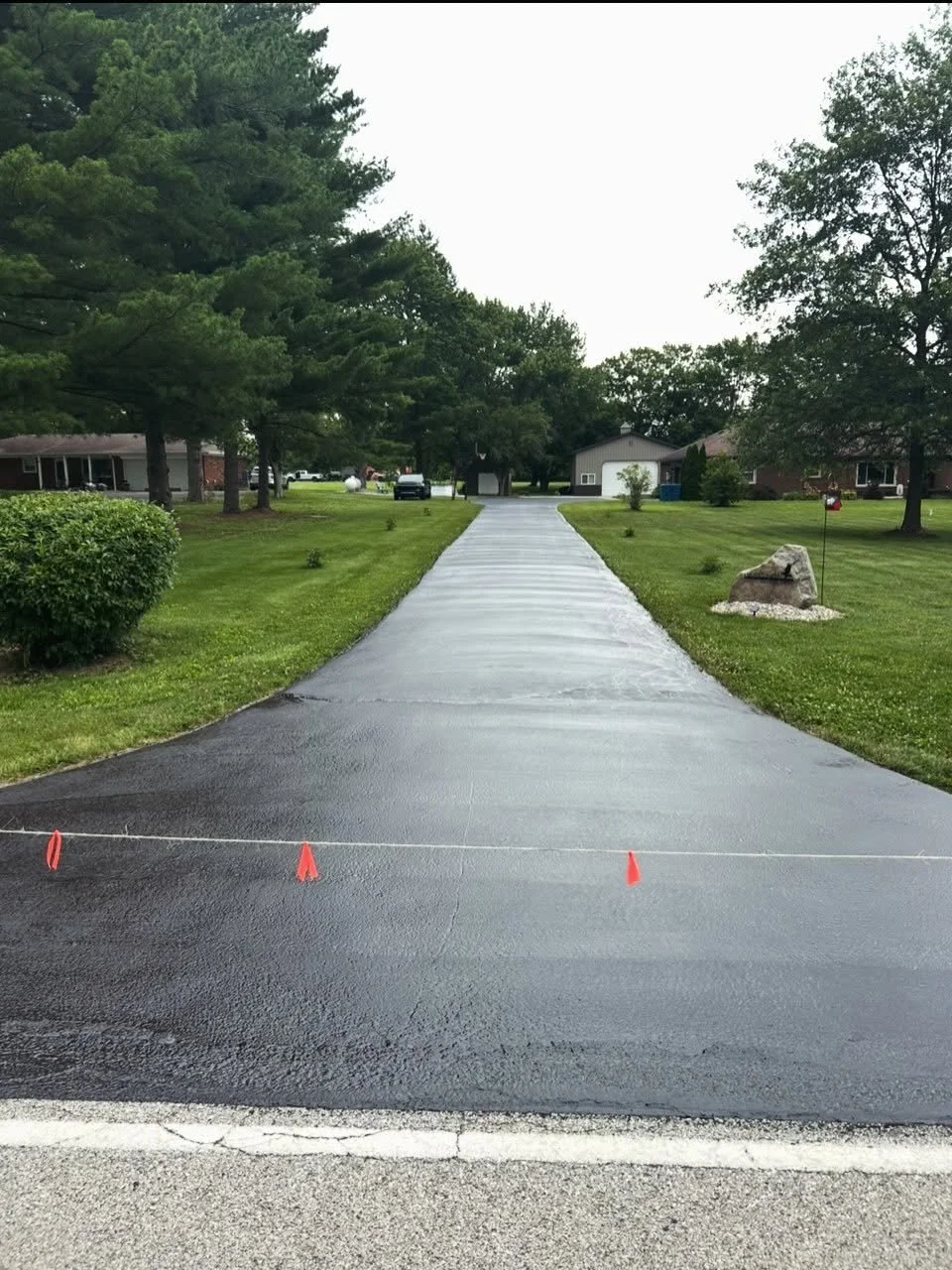 A driveway in Danville, Indiana with a fresh coat of sealer, cracks filled, asphalt repairs and a basketball court striped by Blacktop Boss. 