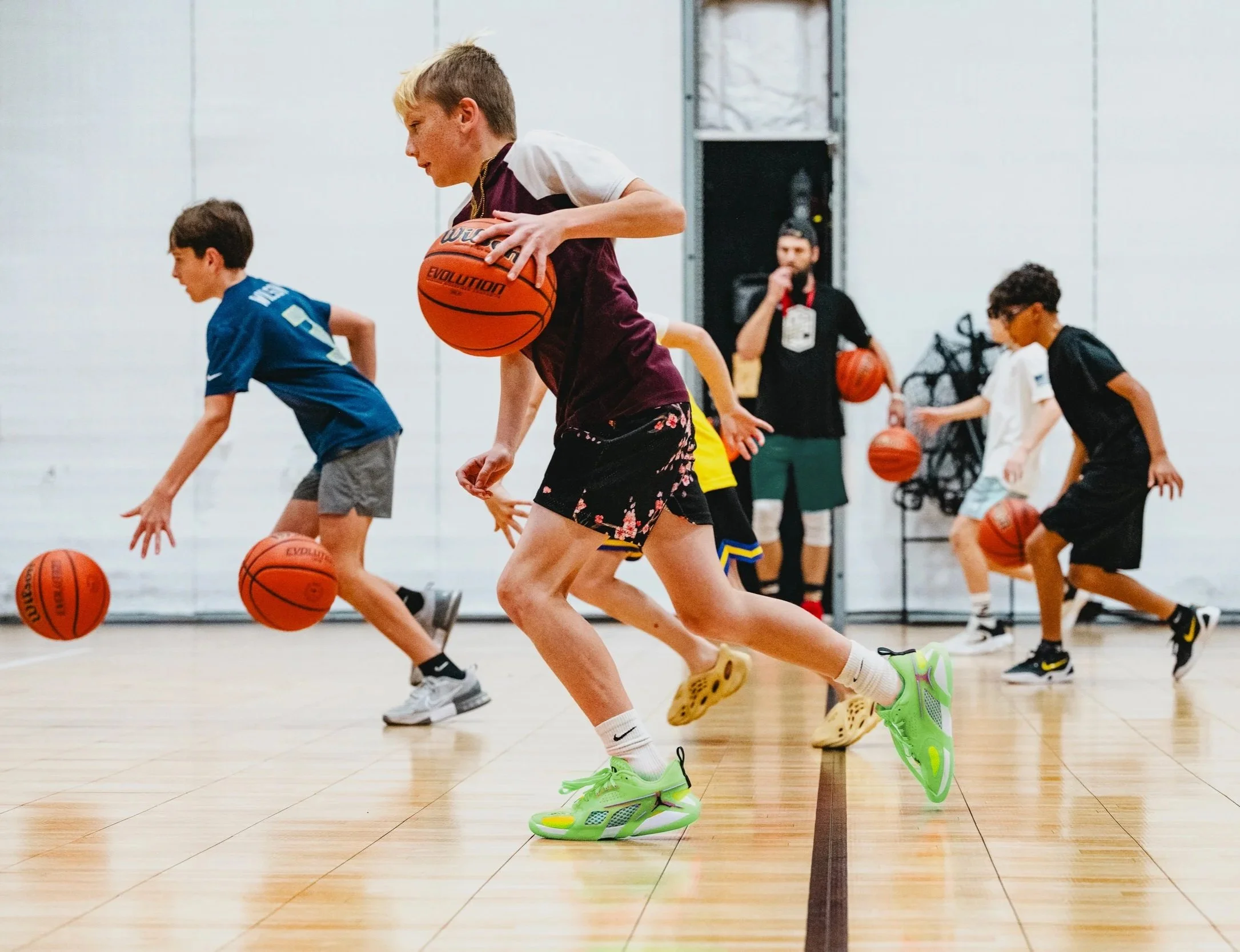 Youth basketball players practicing dribbling drills at indoor training facility in Dripping Springs, TX