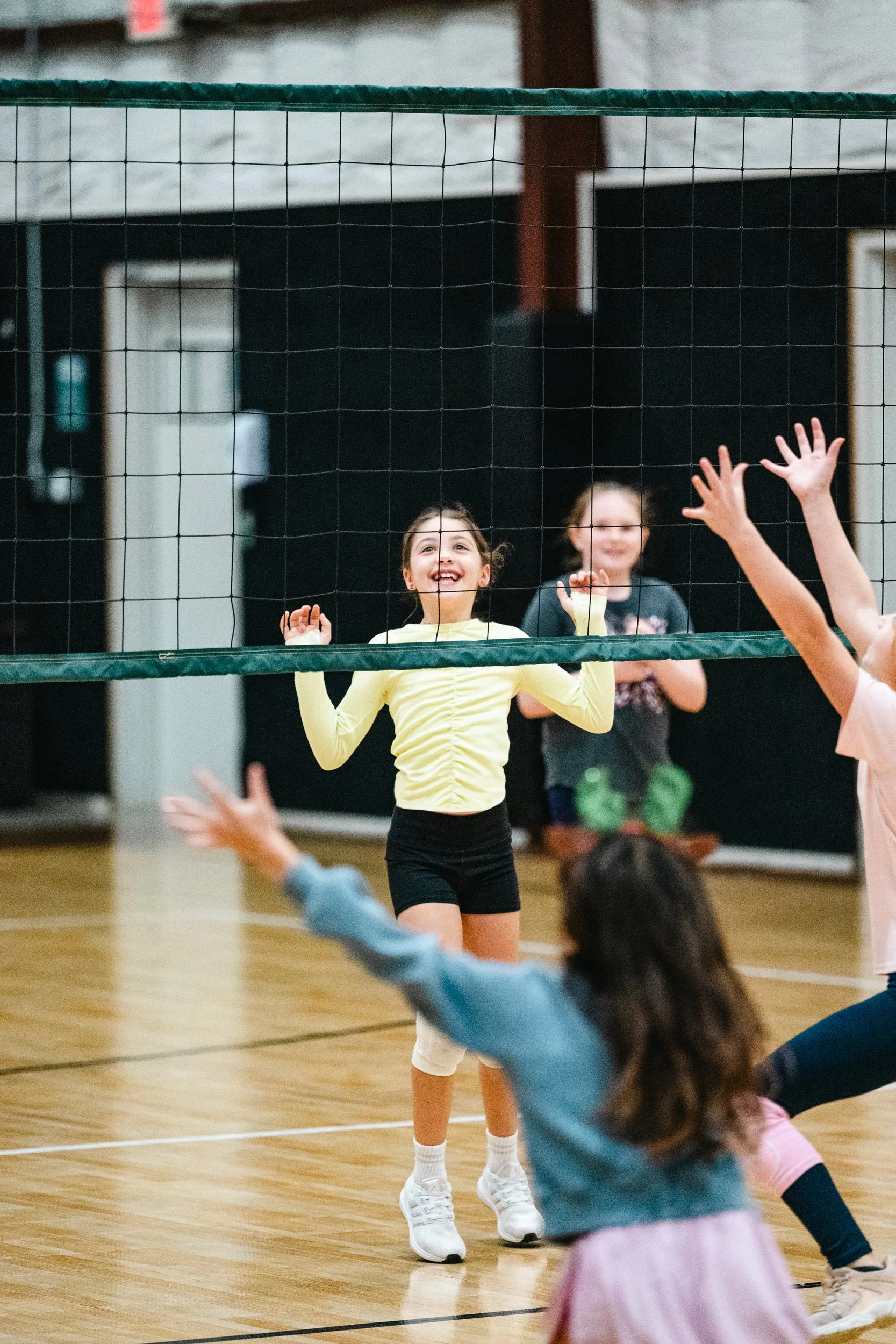 Young volleyball player smiling during team drill at indoor sports facility in Dripping Springs