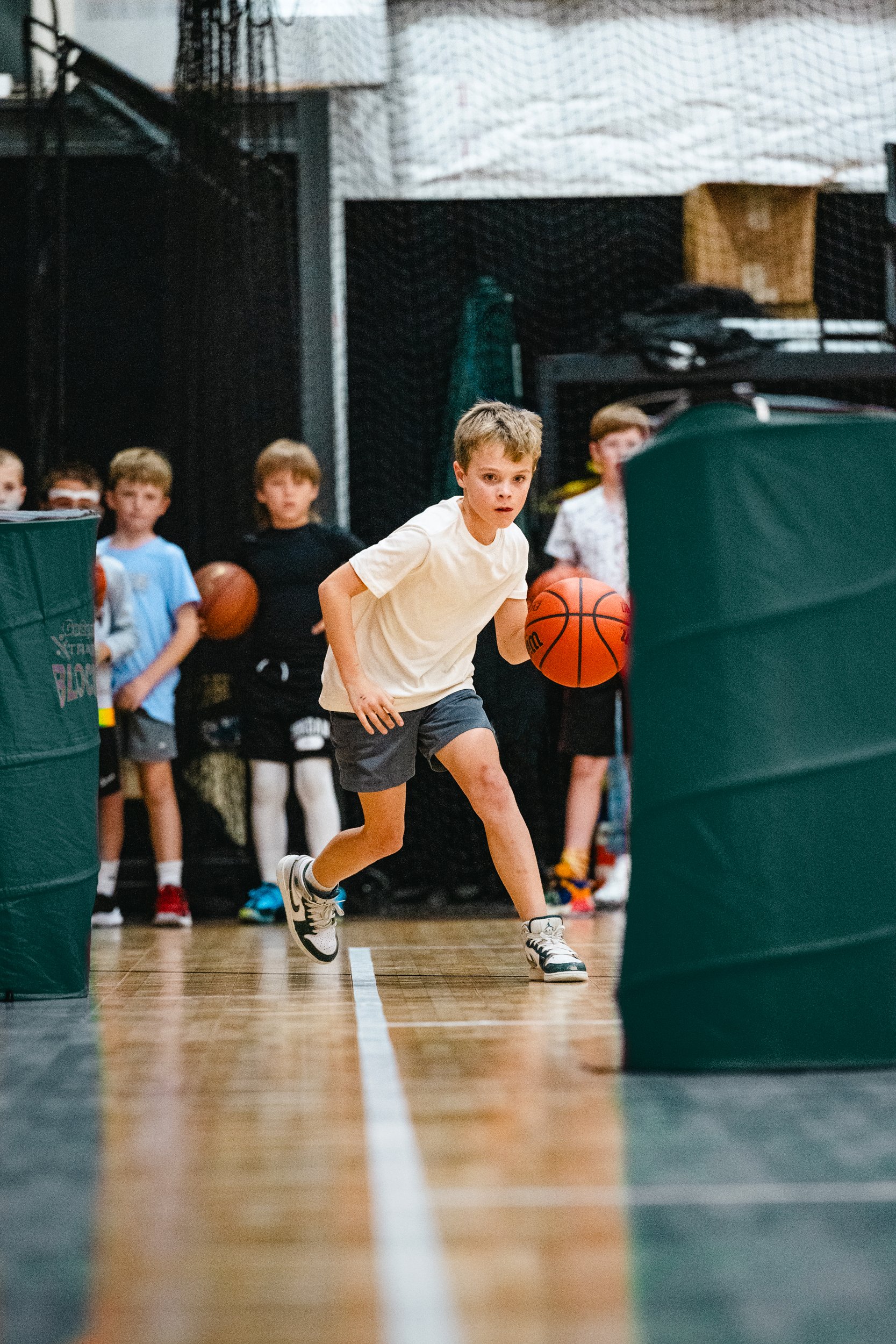 Youth basketball player weaving through training obstacles during skills clinic in Dripping Springs