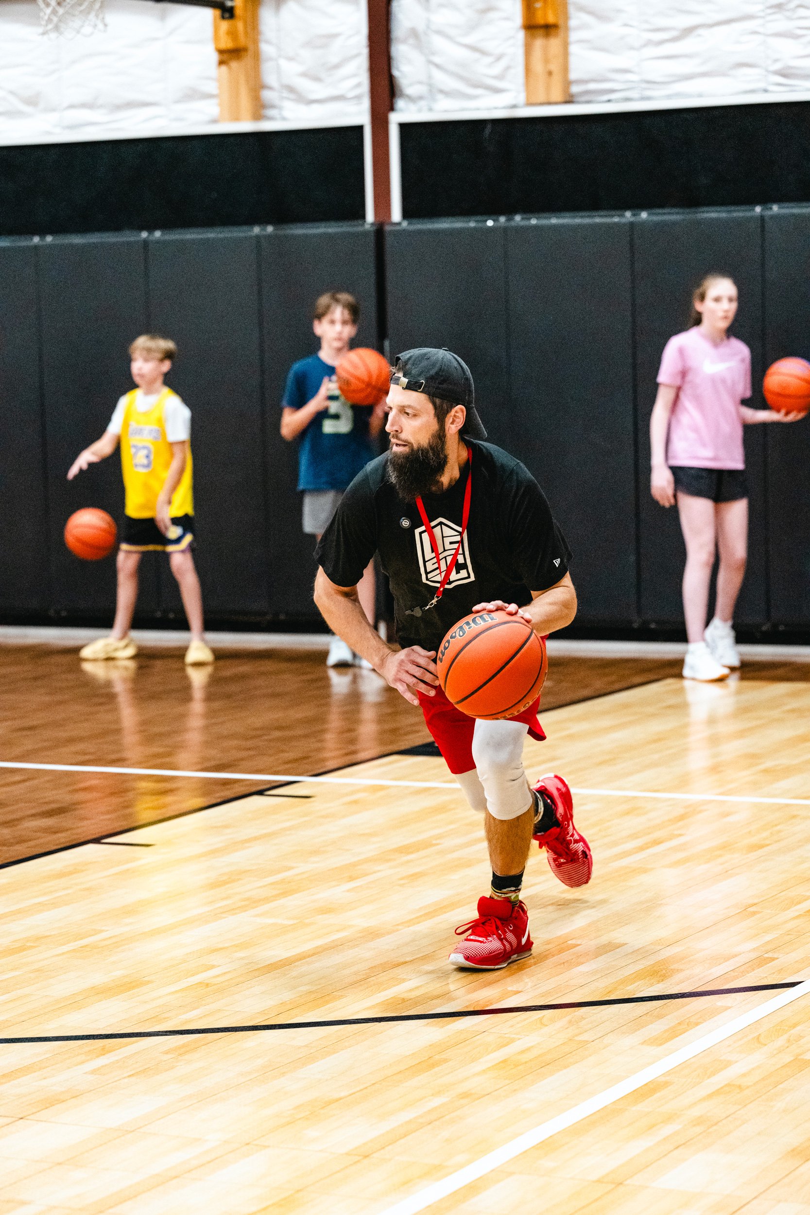 Basketball coach demonstrating ball-handling technique during youth training session in Dripping Springs