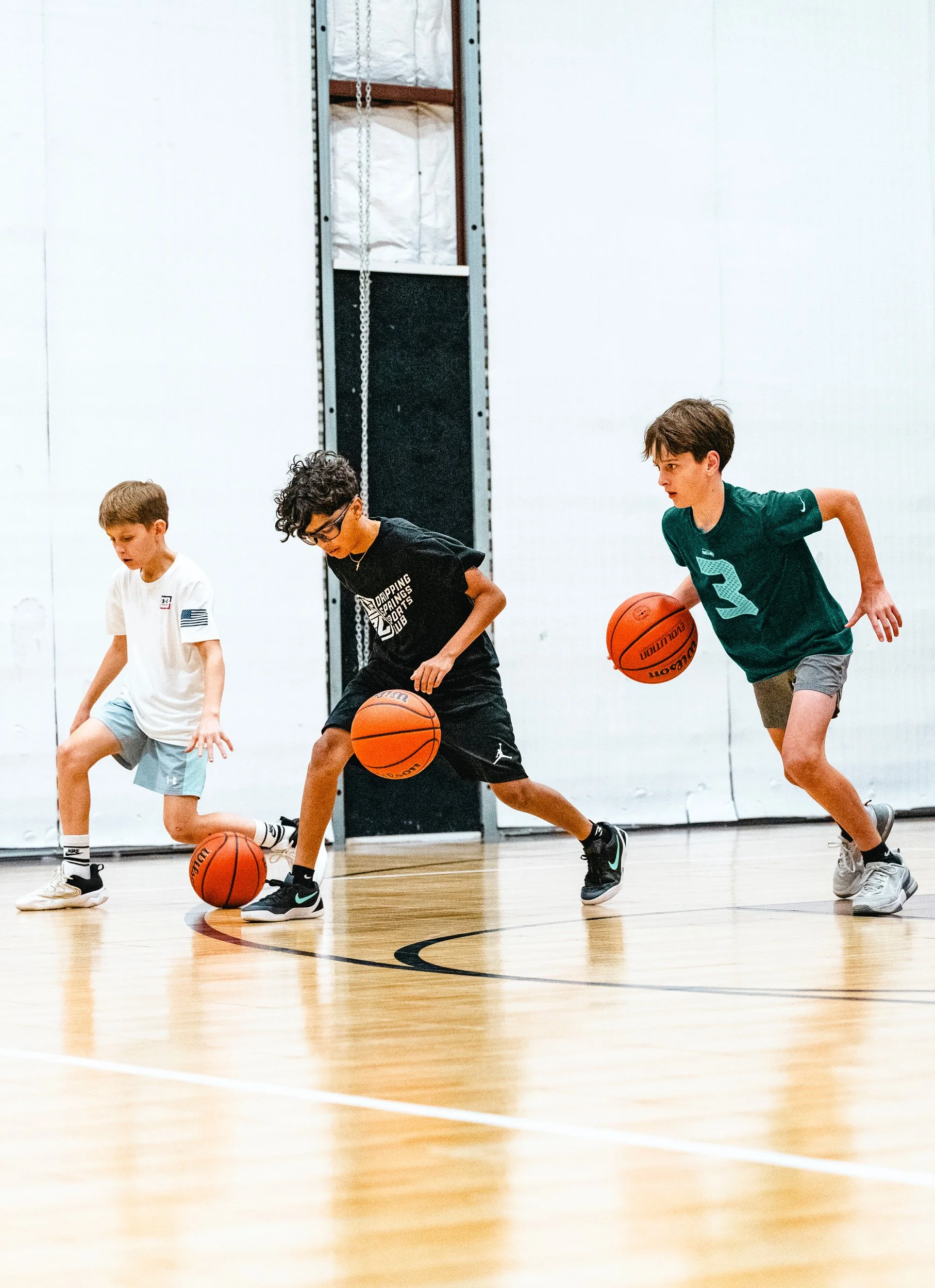 Youth basketball players practicing dribbling and footwork drills during clinic in Dripping Springs
