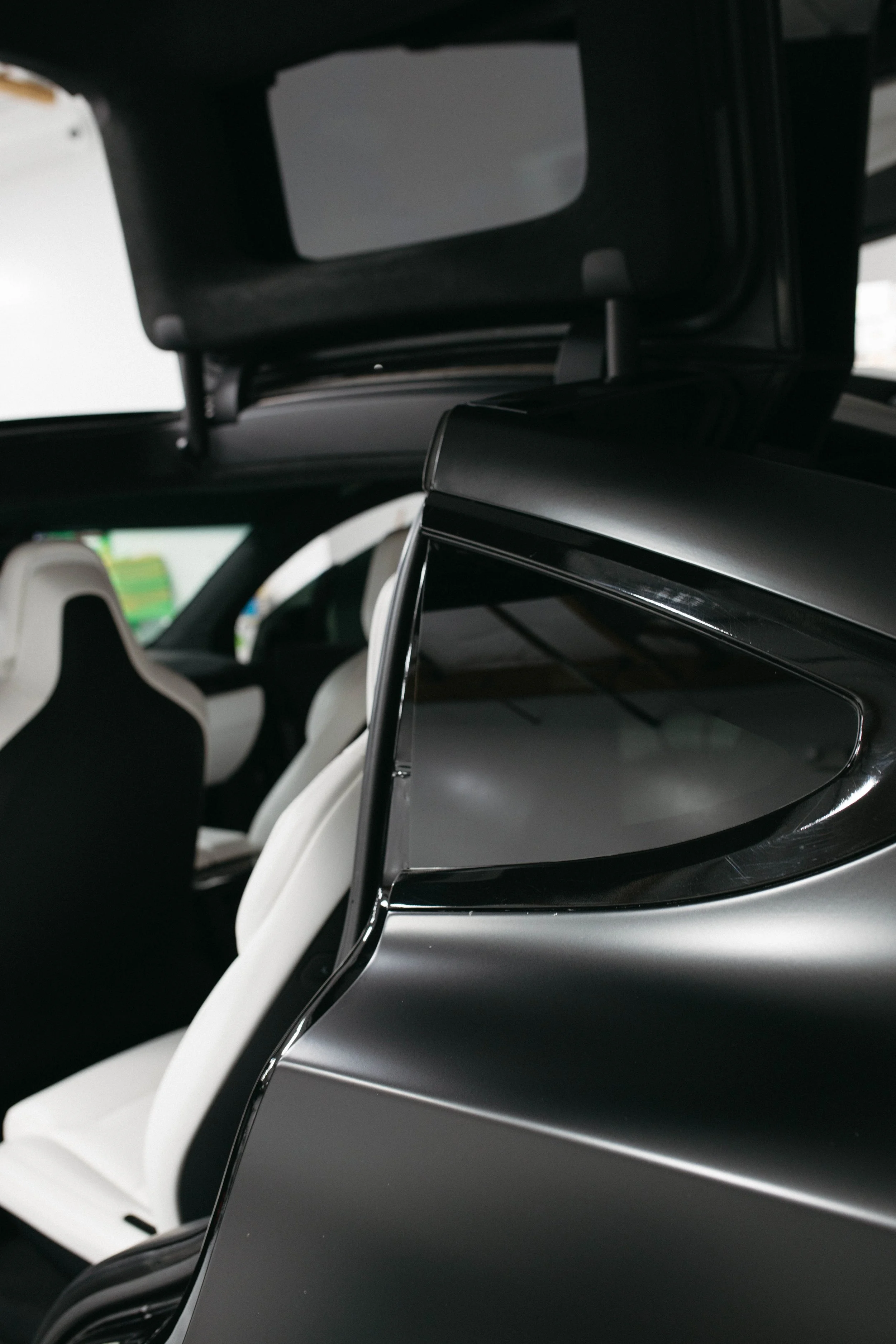 Close-up view of the rear sides of multiple Tesla electric vehicles, showcasing their sleek, modern design and tinted rear windows.