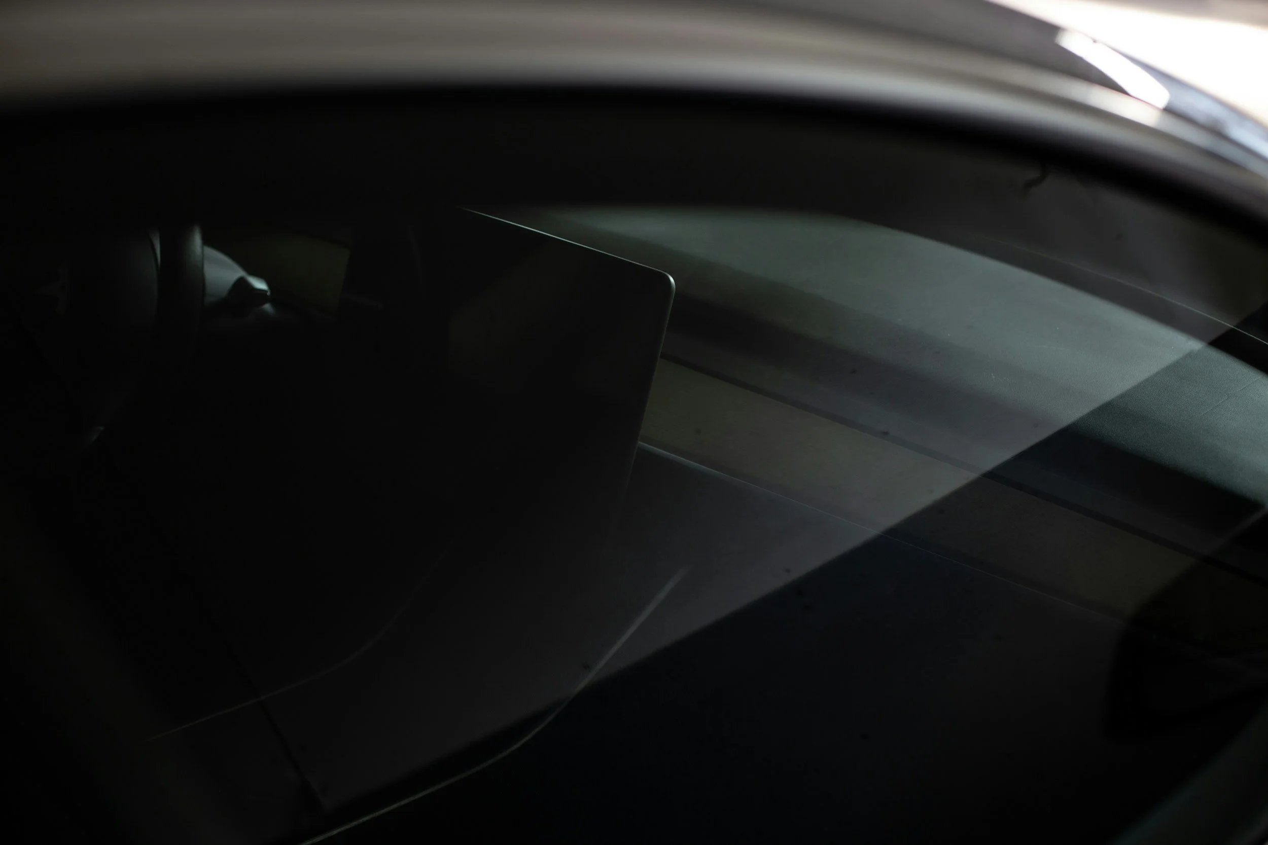 Inside a car showing the dashboard and steering wheel from the front seat, with a focus on the windshield and interior details.