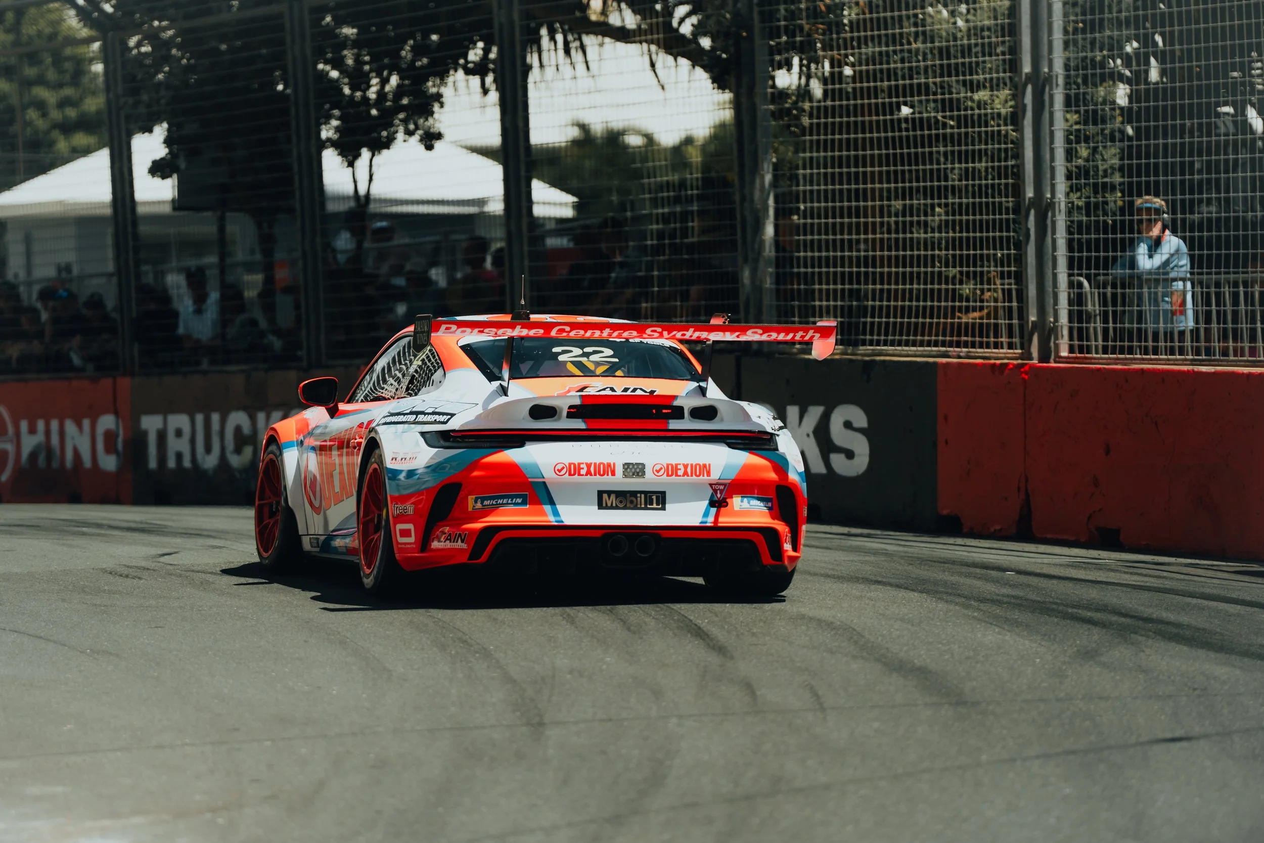 A race car on a track with sponsor logos and the number 22, with spectators in the background behind a fence.