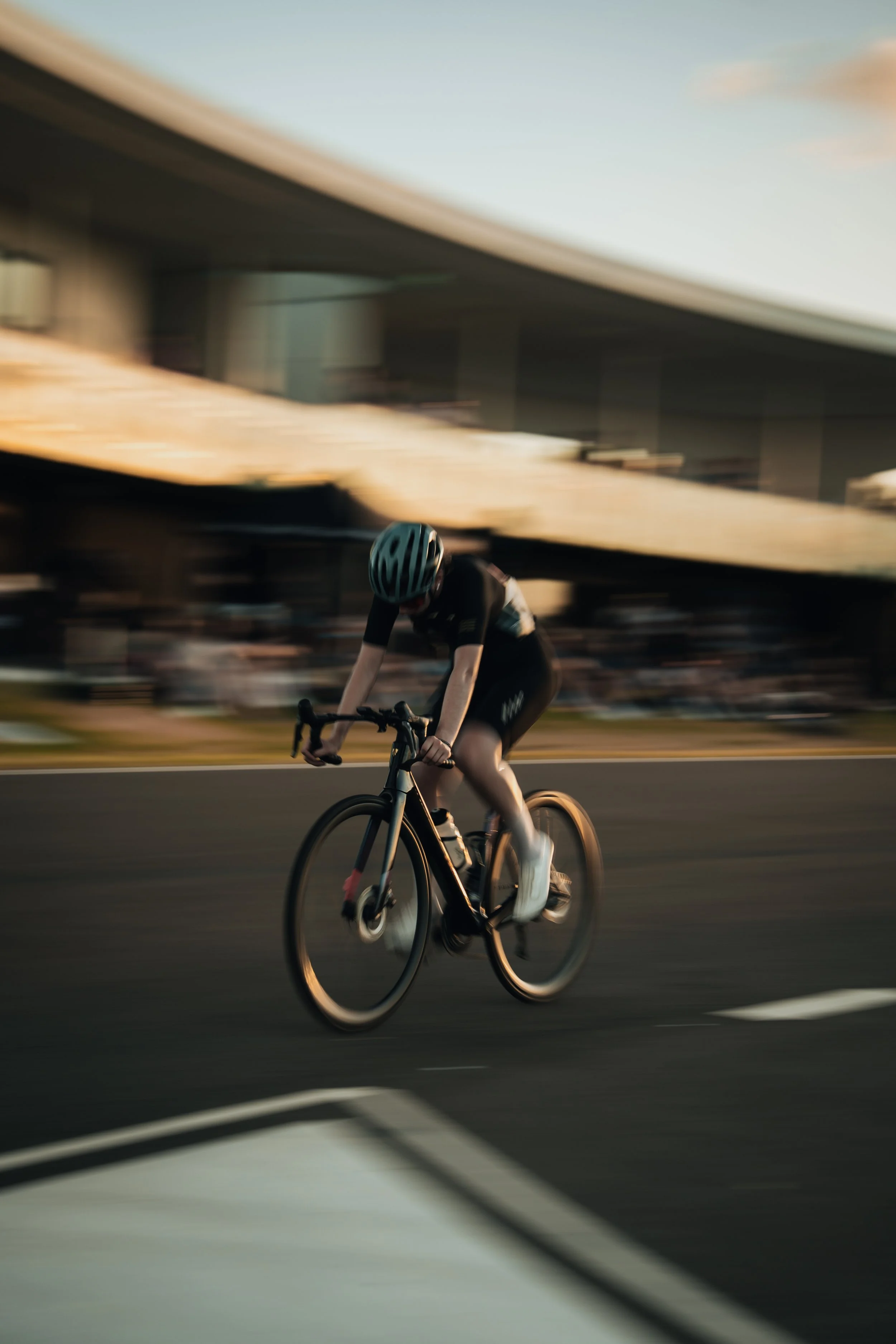 A cyclist wearing a helmet riding a bike on a road with a blurred background, indicating motion.