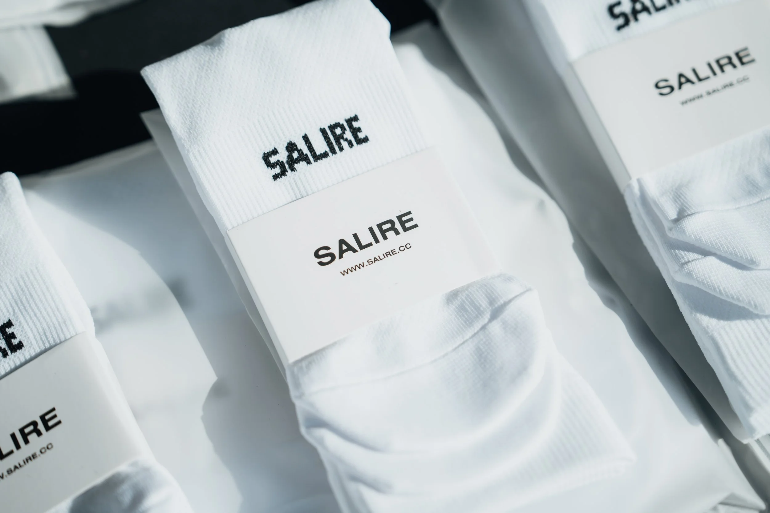 Close-up of white tubes with black text reading 'SALIRE' and website 'WWW.SALIRE.CC' on a white band, arranged on a flat surface.