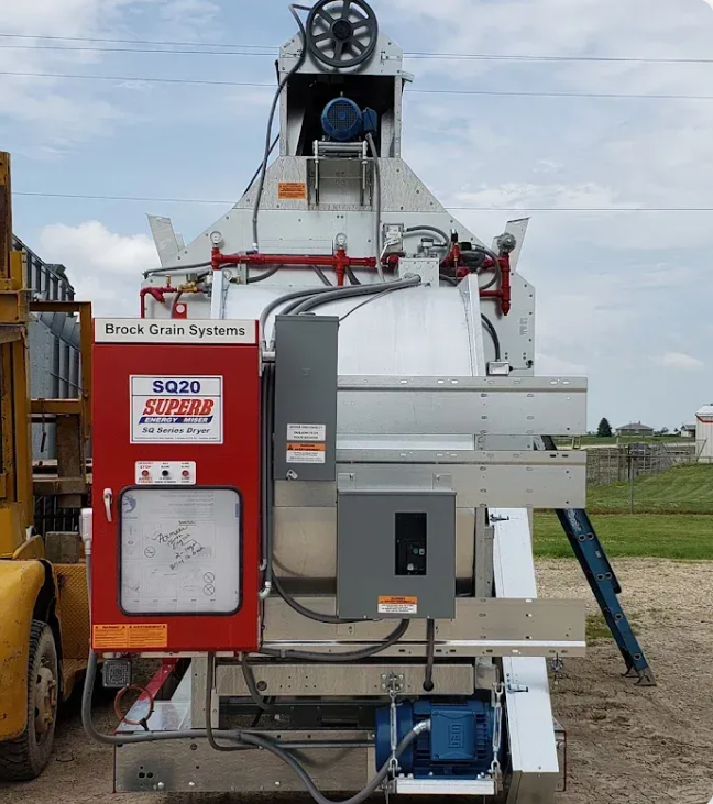 Large industrial grain drying machine outdoors, with the label 'Brock Grain Systems' and 'SQ20 SuperB energy master' on it.