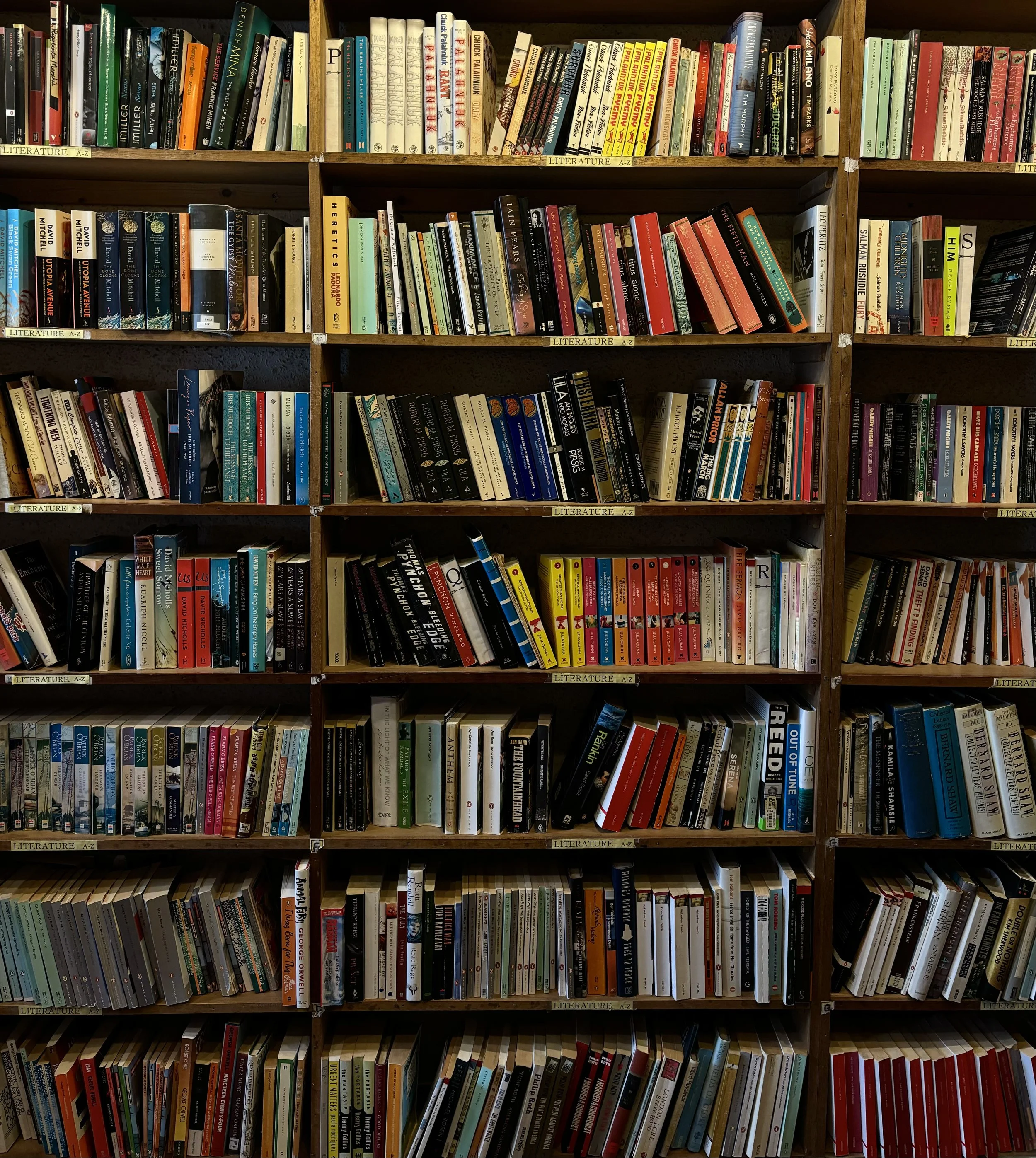 Bookshelves filled with a wide array of books, organized and labeled by genre and alphabetical order.