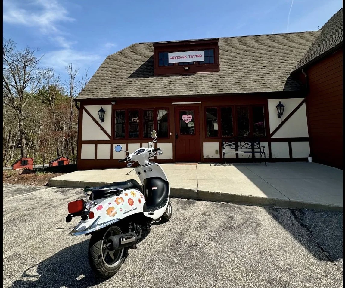 Lovesick Tattoo Studio in Amherst, New Hampshire (Amherst, NH).  Front of the tattoo studio with a cute motorcycle parked out front.  Swiss building design.  Cute and funky style, pink and white branding.