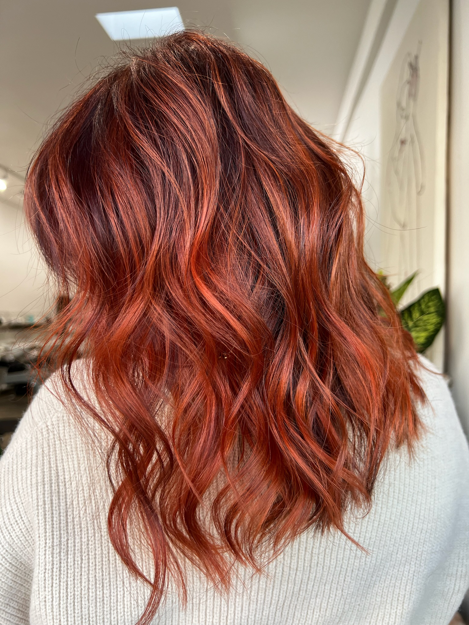 Close-up of a woman's wavy hair with red and copper tones.
