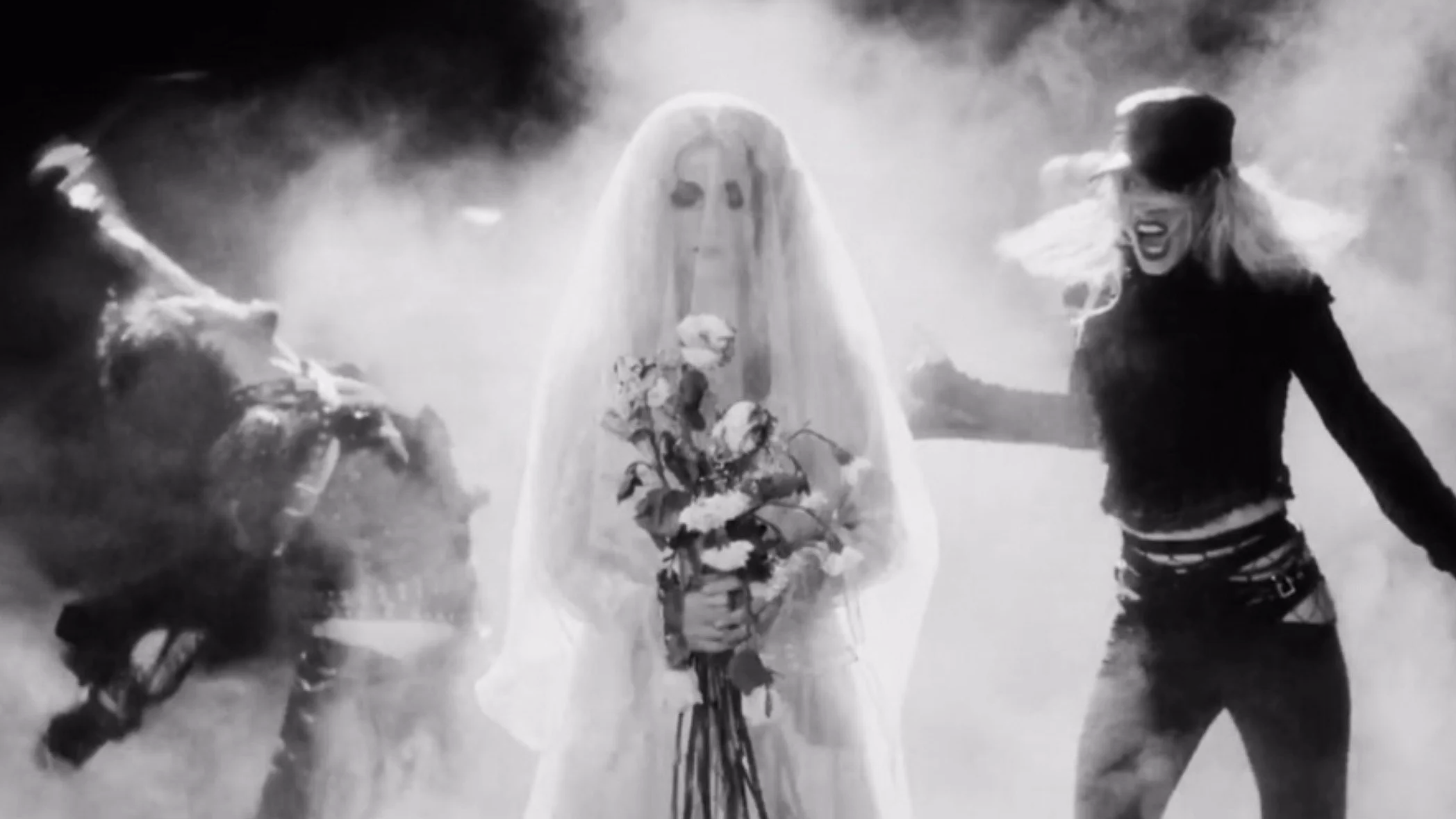 Black and white image featuring two women, one on the left with spiky hair and the other on the right with a hat and long hair, both appearing to be shouting or in intense emotion, with a third figure in the center wearing a veil and holding a bouquet of flowers.