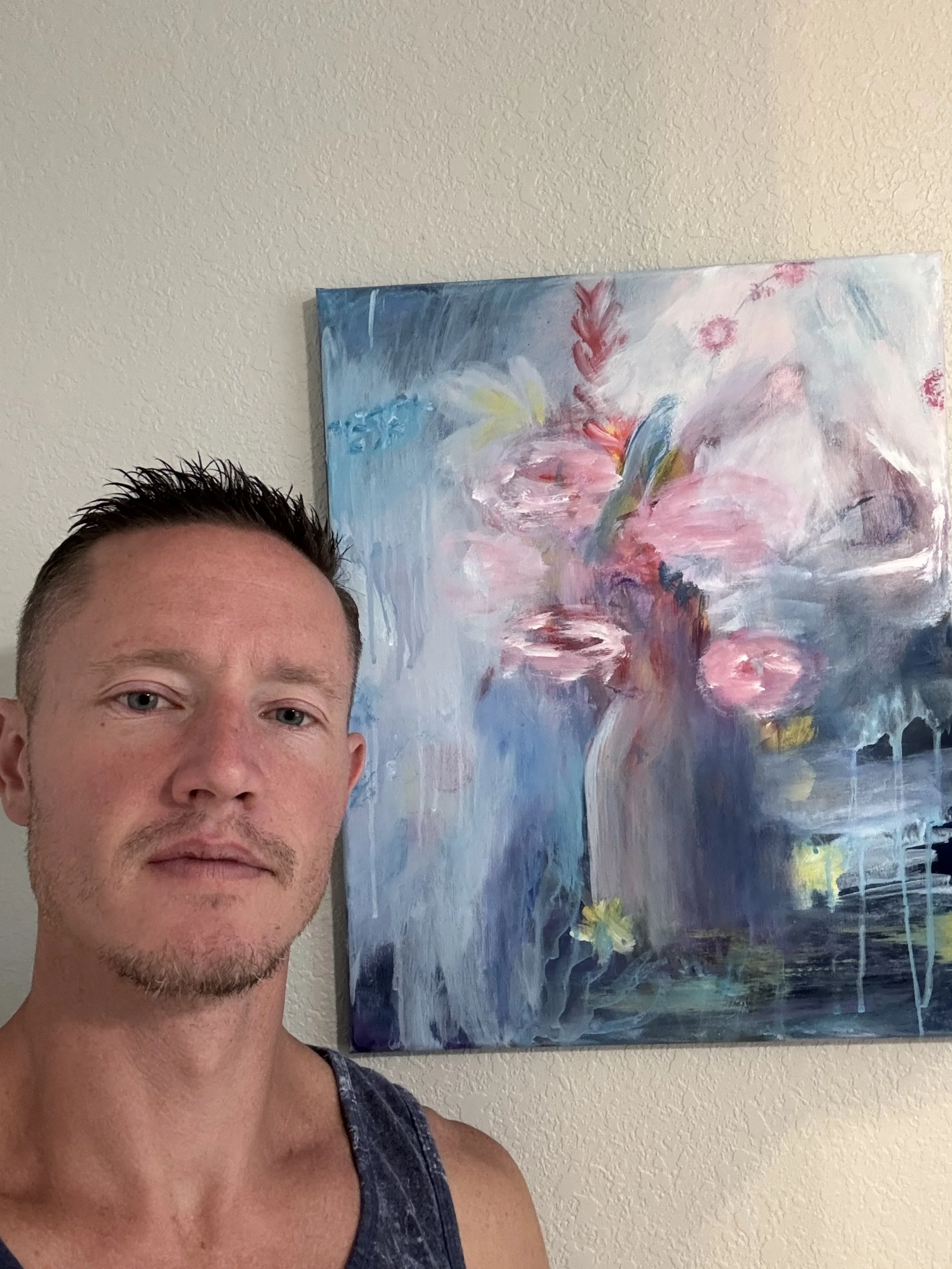 This is an image of Rob King the artist in front an abstract flower painting.